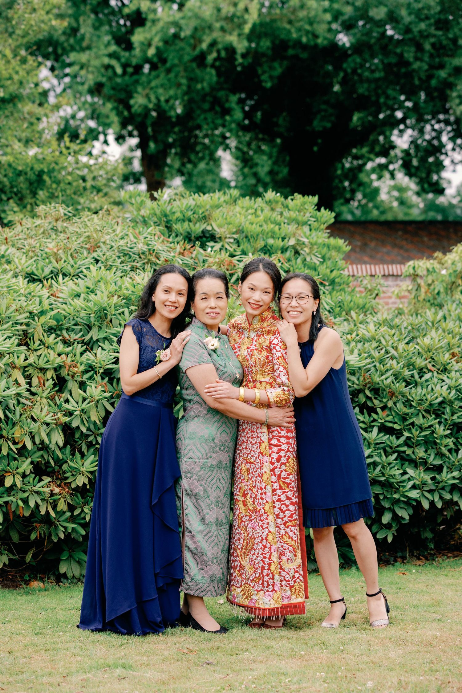 A group poses together outdoors on grass wearing blue dresses and floral prints in a casual garden setting.