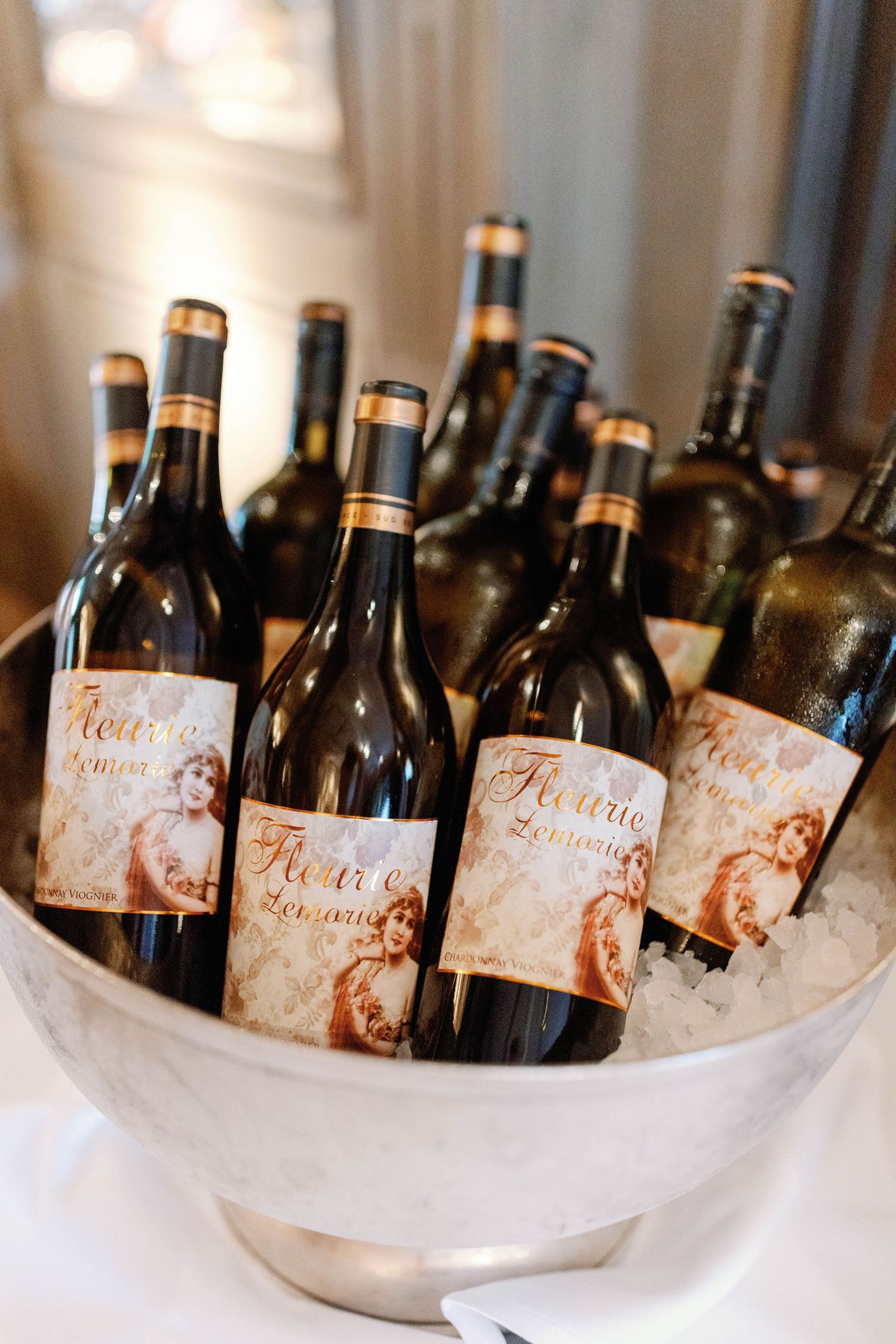 Multiple wine bottles with matching labels chilling in ice buckets at an elegant event setting.