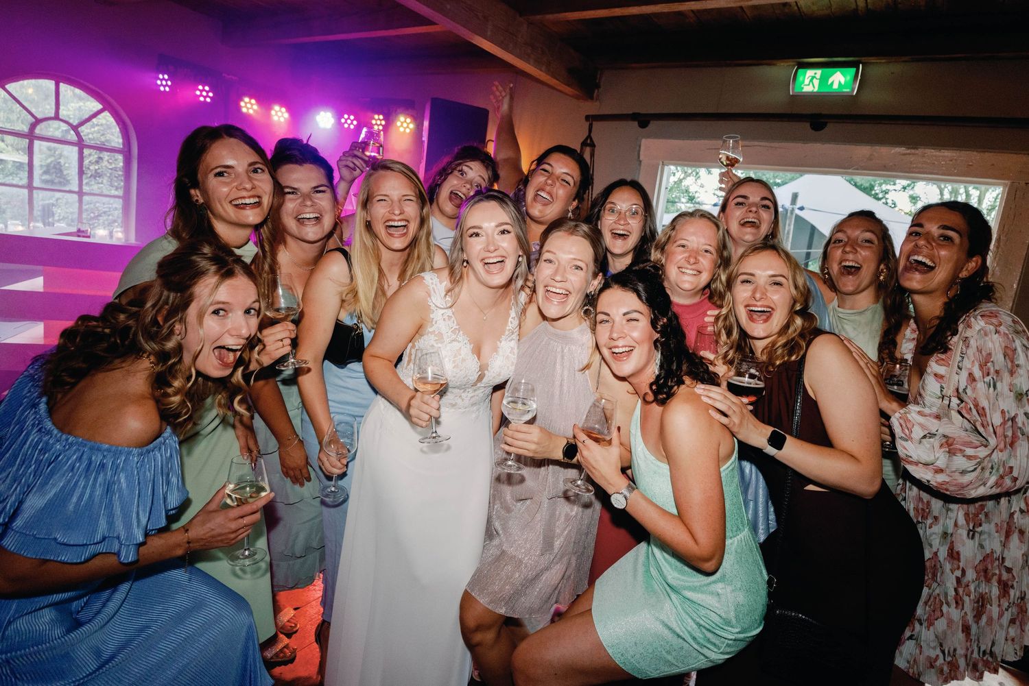 A group of people dancing and celebrating together at a nightclub with colorful lighting and festive atmosphere.