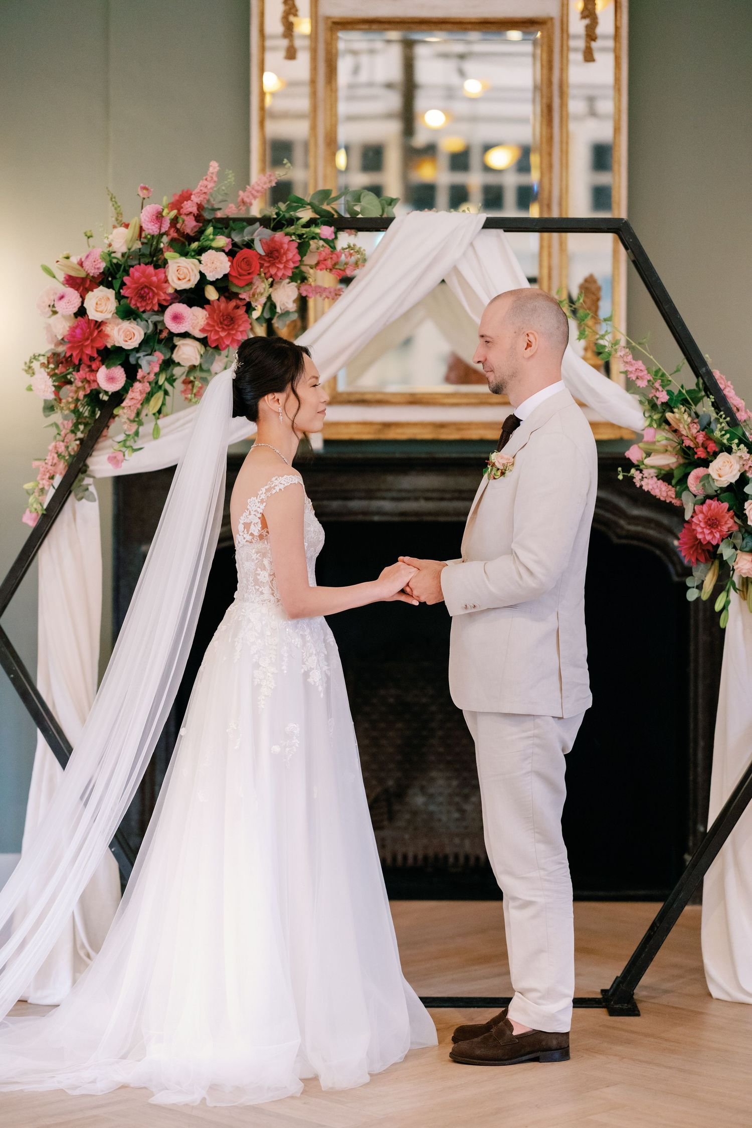 Wedding ceremony setup with black geometric arch decorated with pink and white floral arrangements.