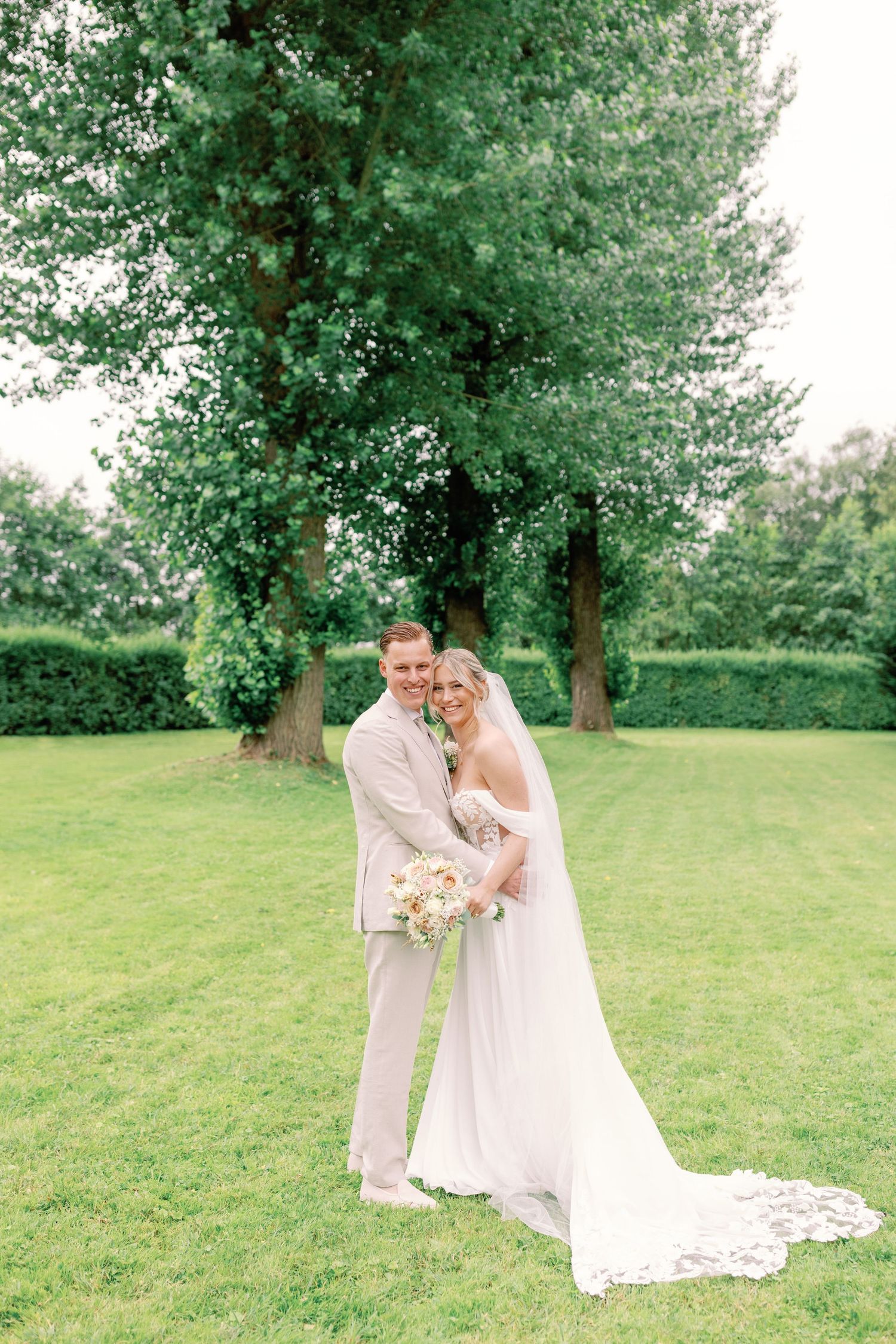 Romantic wedding portraits in a lush green garden setting with flowing white dress and veil.