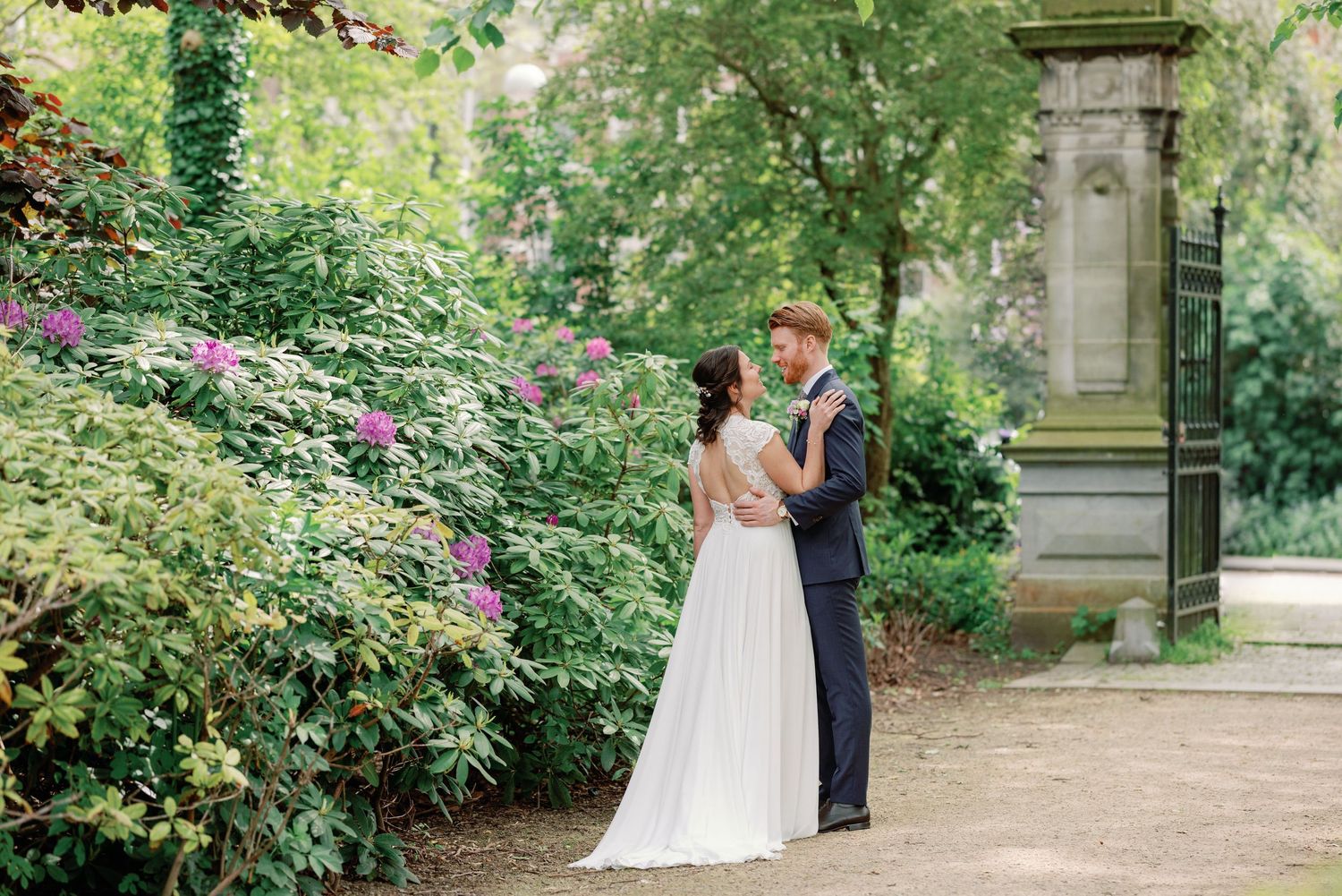 A couple shares romantic moments in a lush garden setting during their wedding photoshoot.