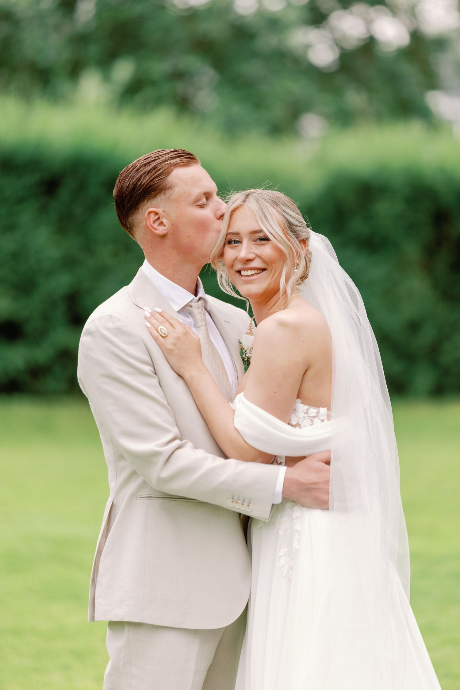 Couple in wedding attire sharing intimate moment in outdoor garden setting.