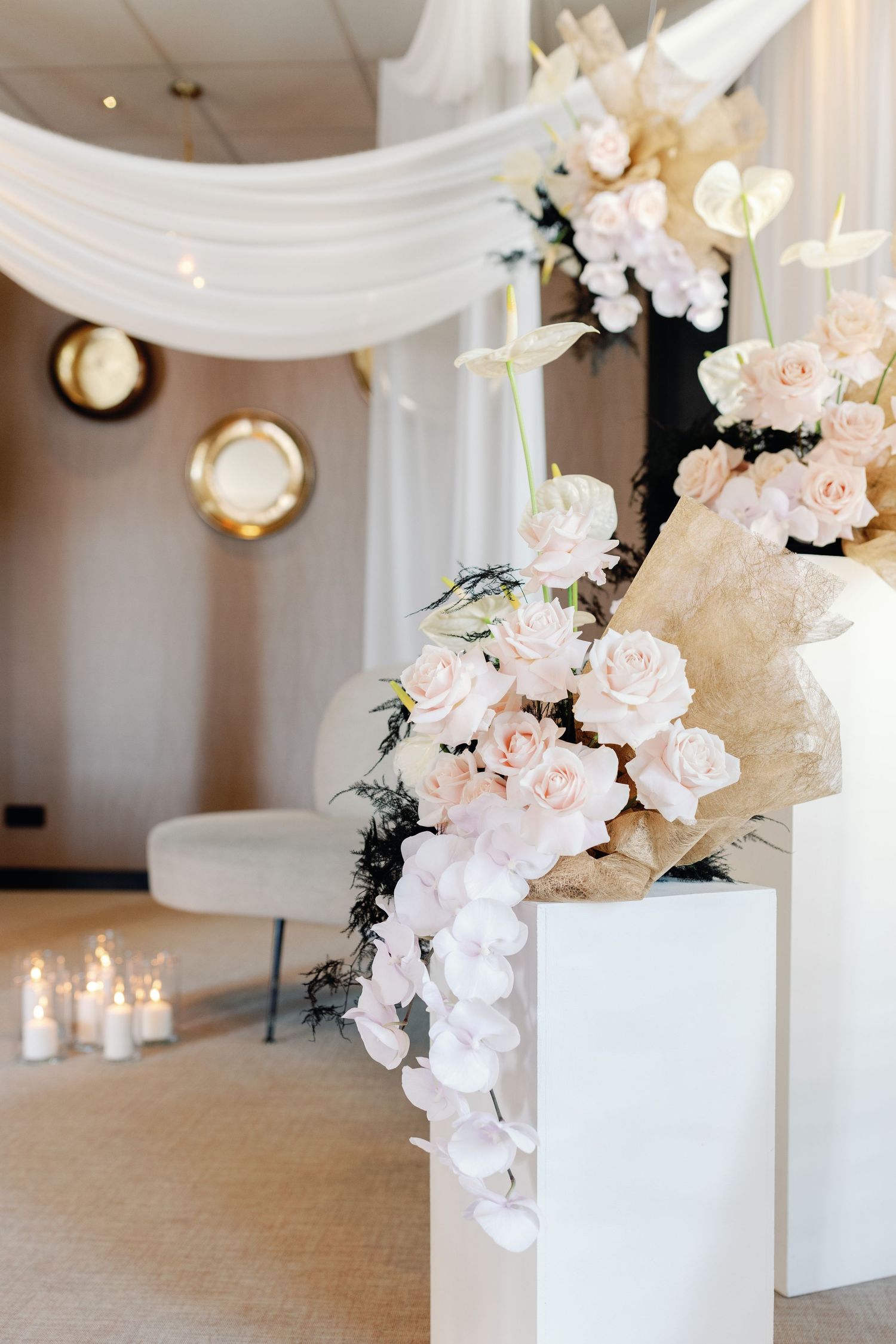 White floral arrangements in modern vases with elegant draping and candlelight decor.
