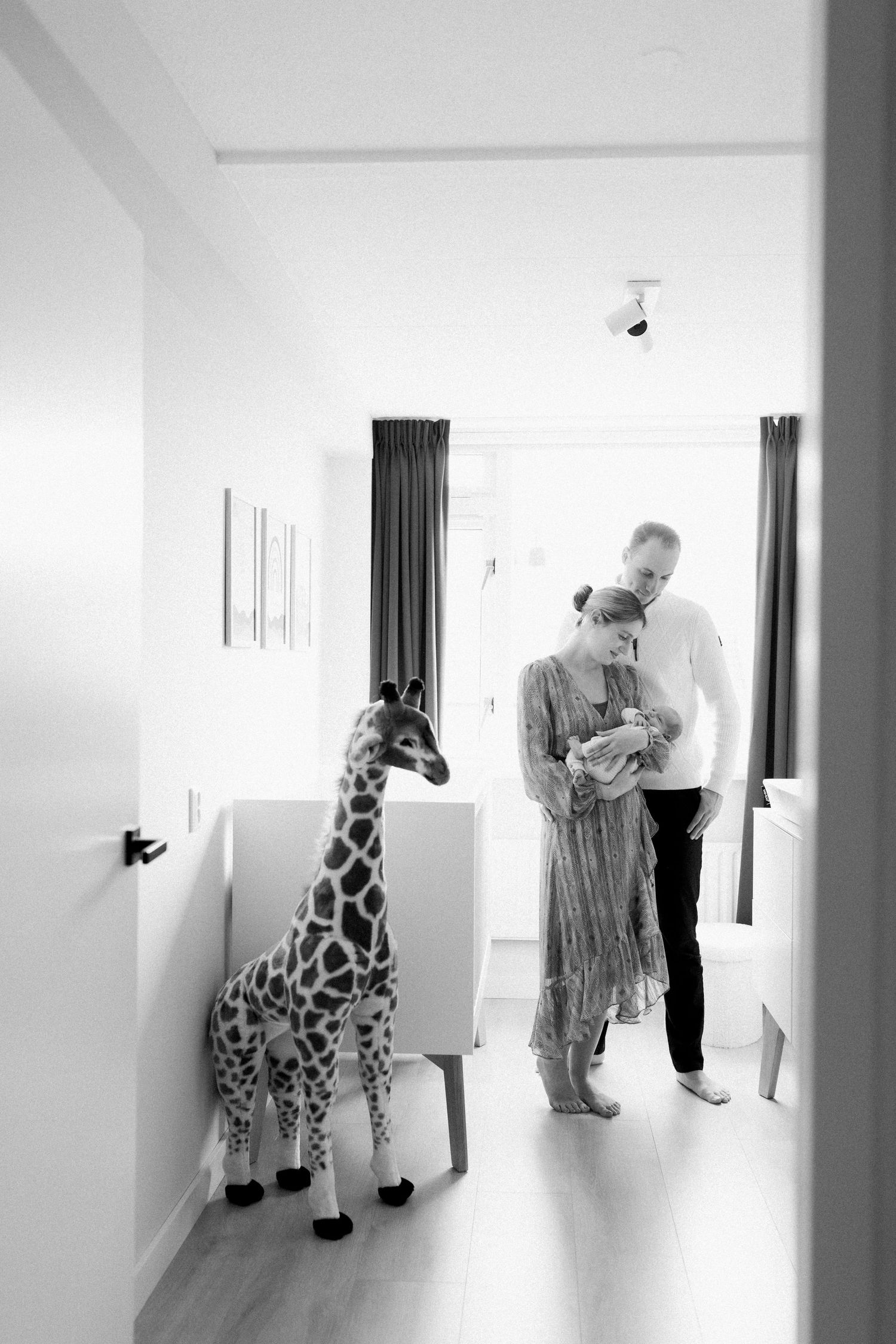 A nursery room scene with a large decorative giraffe and figures in soft lighting.