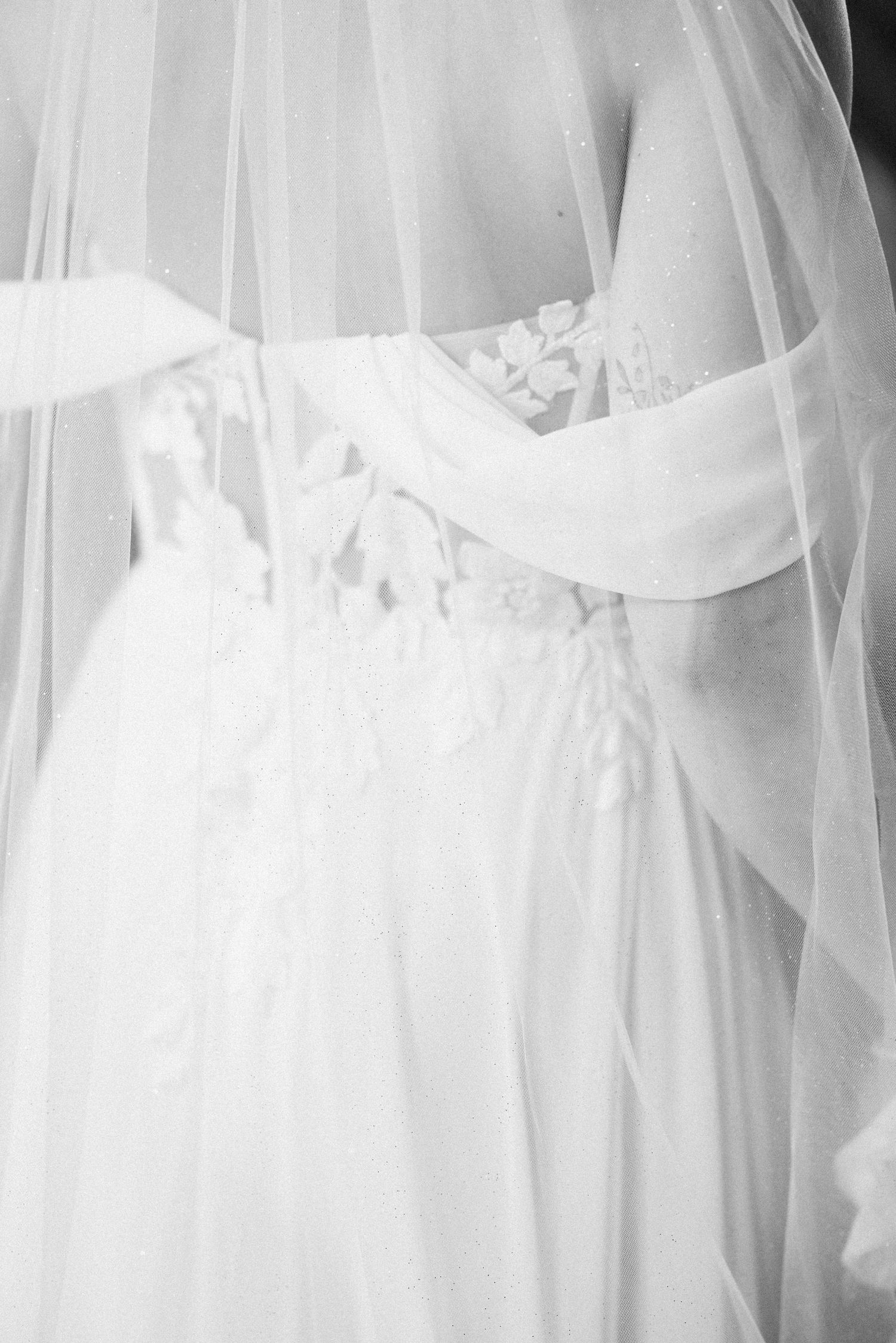 Close-up black and white detail of a wedding dress with delicate veil and lace bodice detailing.