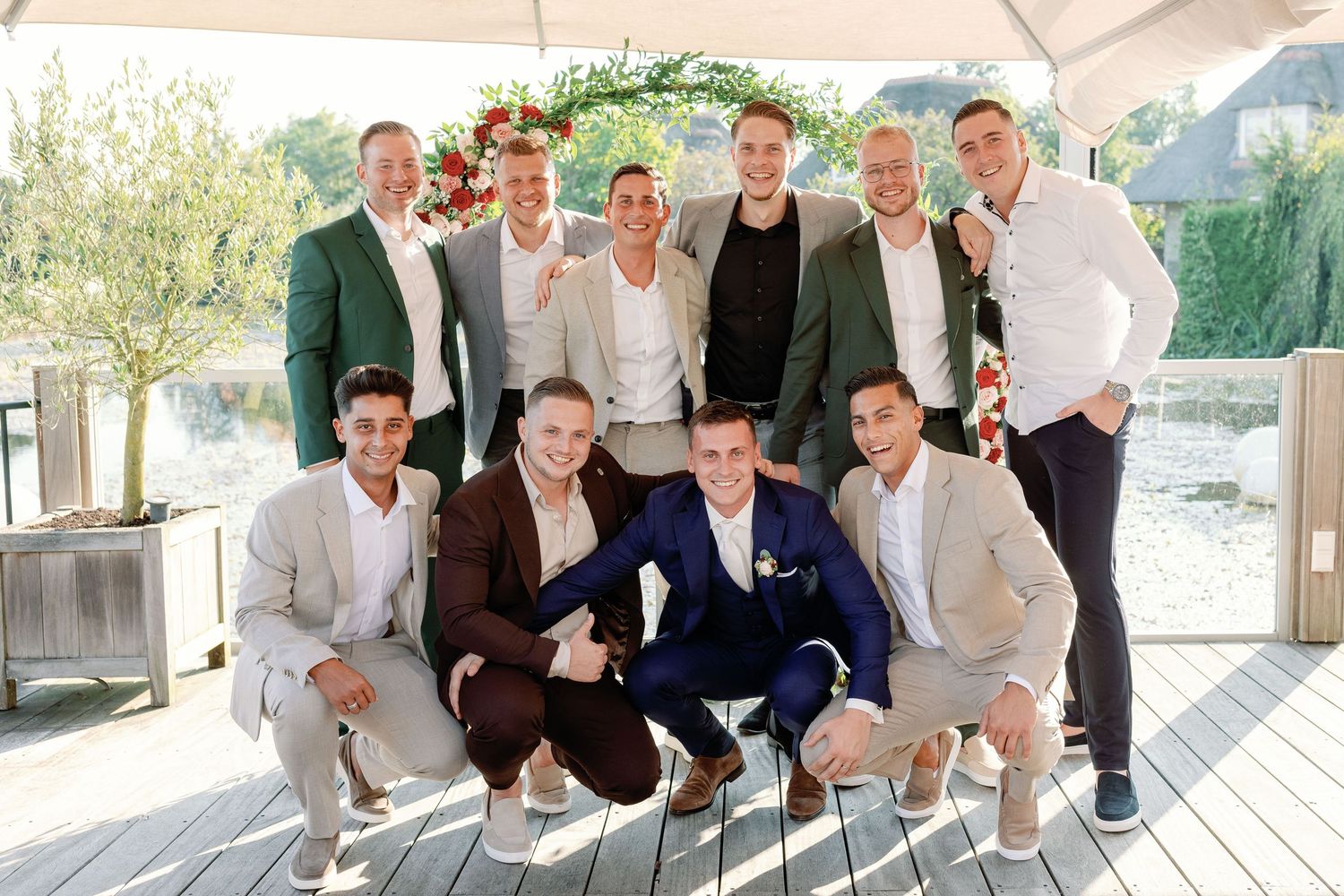 Wedding party in navy and white attire poses casually on wooden deck.