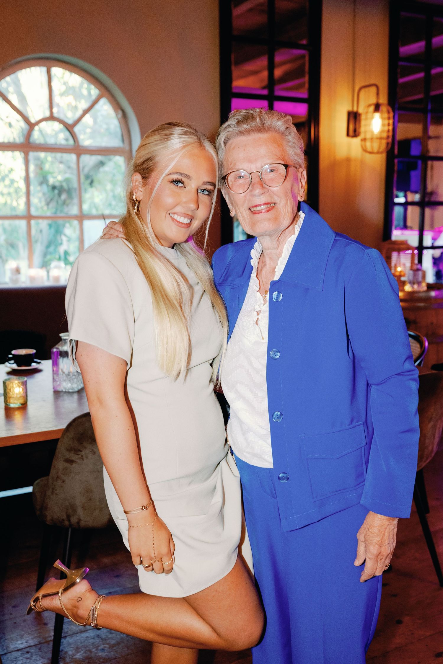 A series of photos showing a young woman in beige posing with an elderly person wearing bright blue attire.