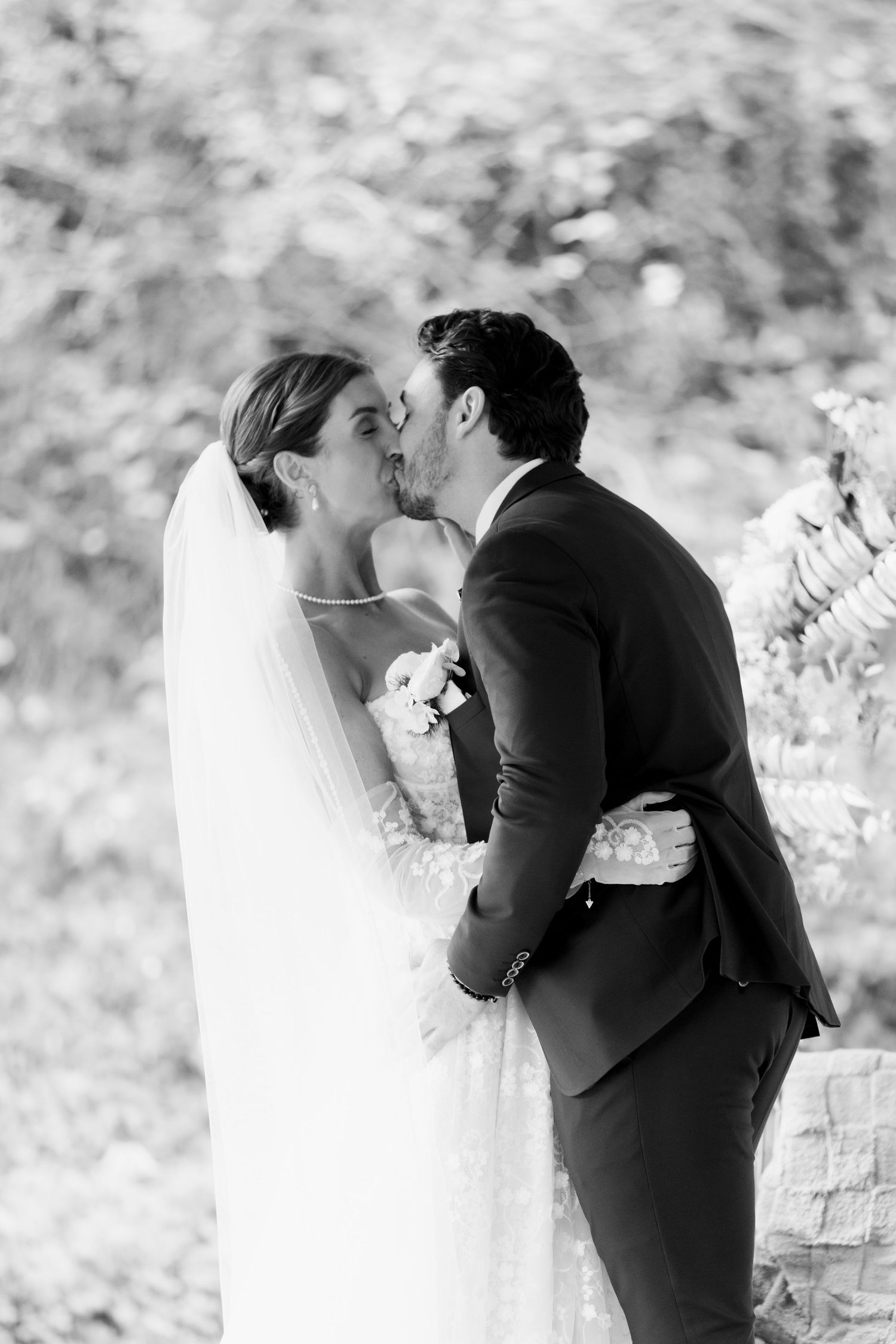 A romantic black and white wedding photo sequence showing a couple sharing their first kiss as newlyweds.