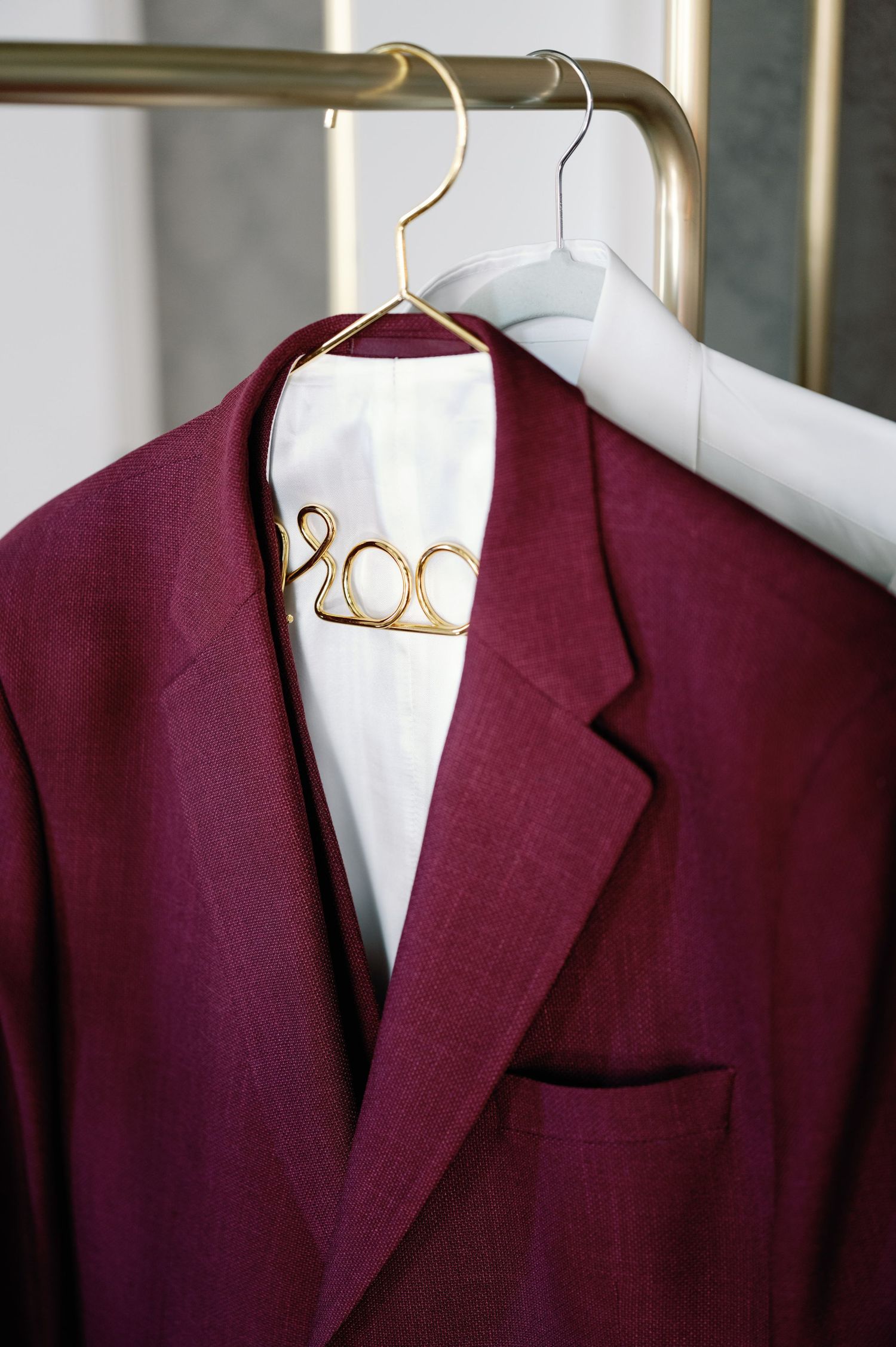 Close-up view of a burgundy wool blazer lapel displayed on a white mannequin against light background.