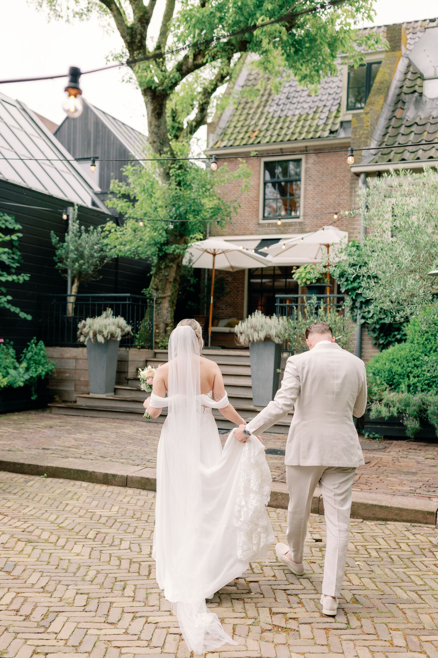 A couple in wedding attire walks together across a brick courtyard in a series of romantic candid moments.