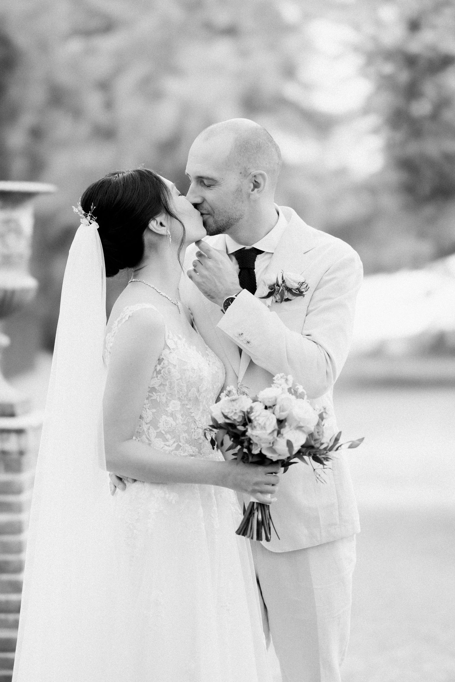 Black and white wedding photo series showing romantic moments between bride and groom with floral bouquet in outdoor setting.