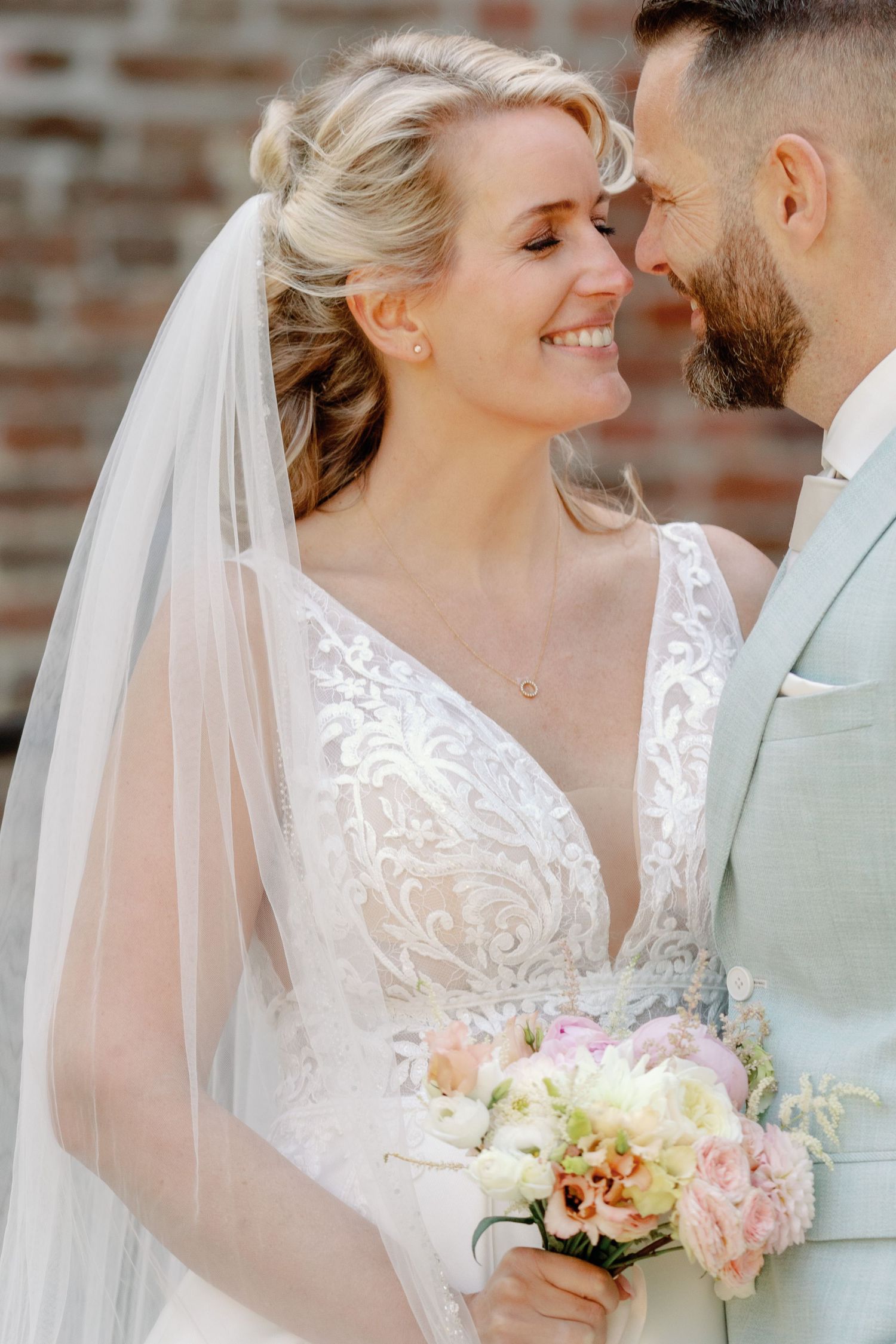Romantic wedding portrait series showing tender moments between newlyweds with bride in lace dress and flowing veil.