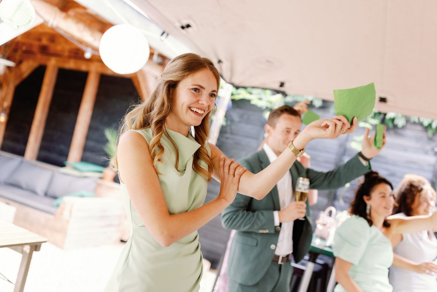 Wedding guests dance and celebrate together during a lively reception on a sunny outdoor patio.