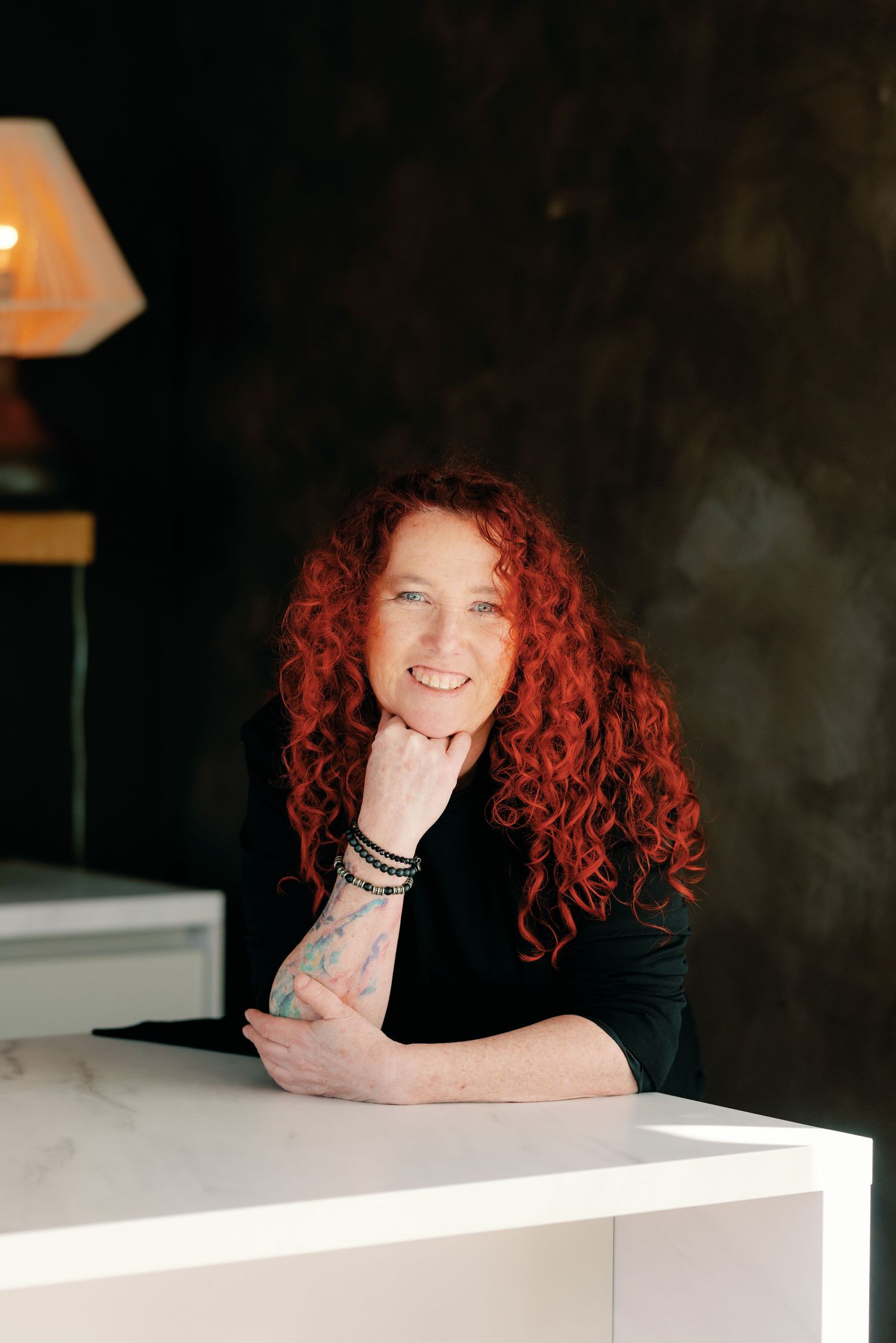 A series of artistic portraits featuring vibrant red curly hair against a dark background with white surfaces.