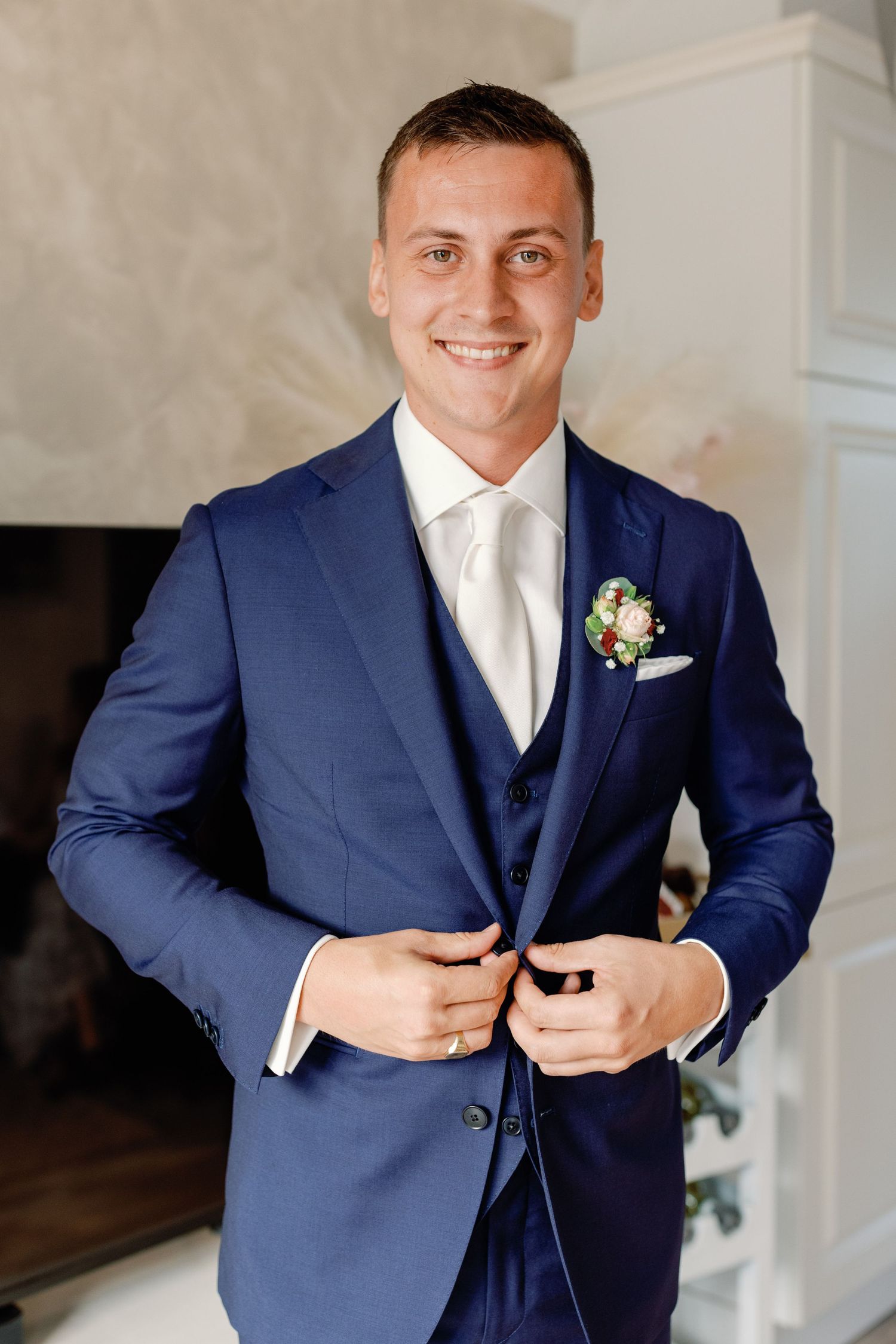 Groom adjusts his navy blue three-piece suit while getting ready for the ceremony.