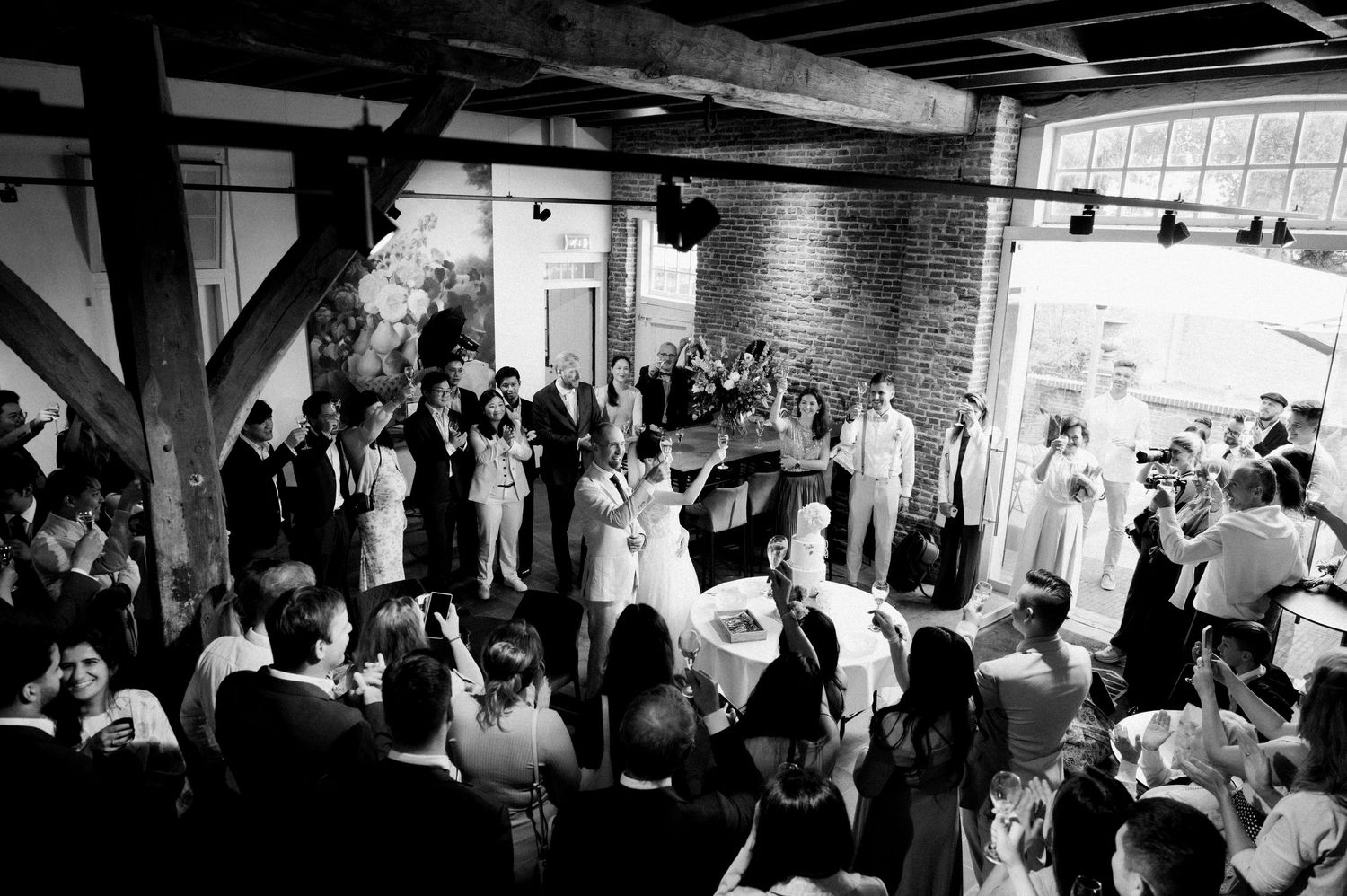 Wedding guests dance and celebrate together on a dimly lit dance floor during an evening reception.