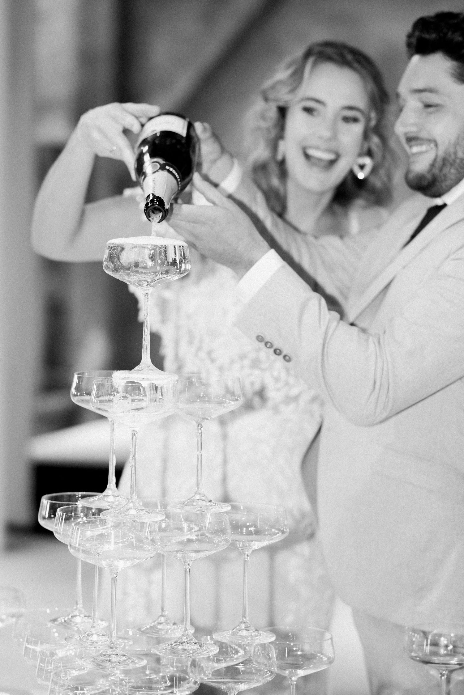 Champagne tower being filled with sparkling wine at an elegant wedding celebration.