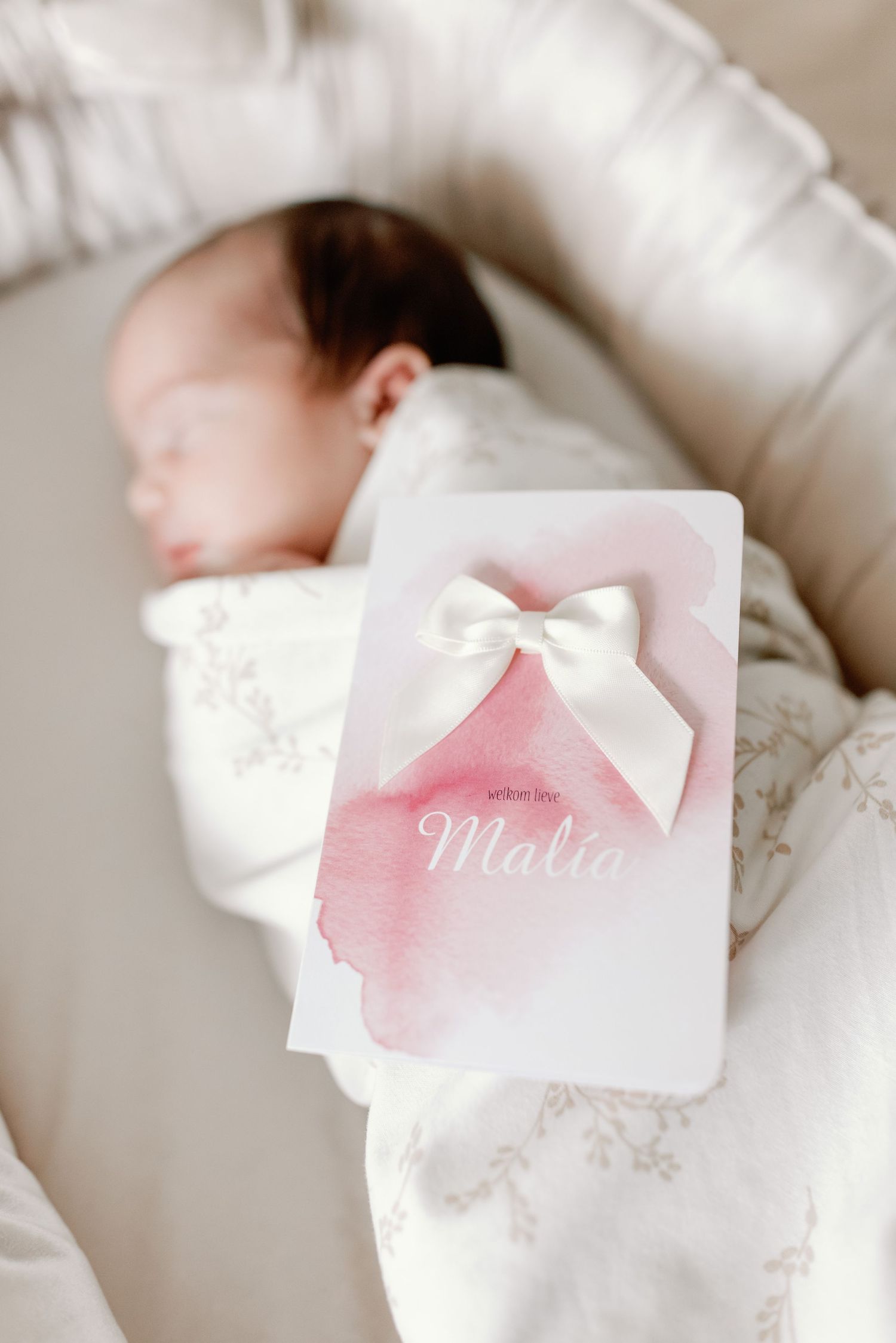 Soft white and pink watercolor wedding invitations with delicate bows displayed in a row.