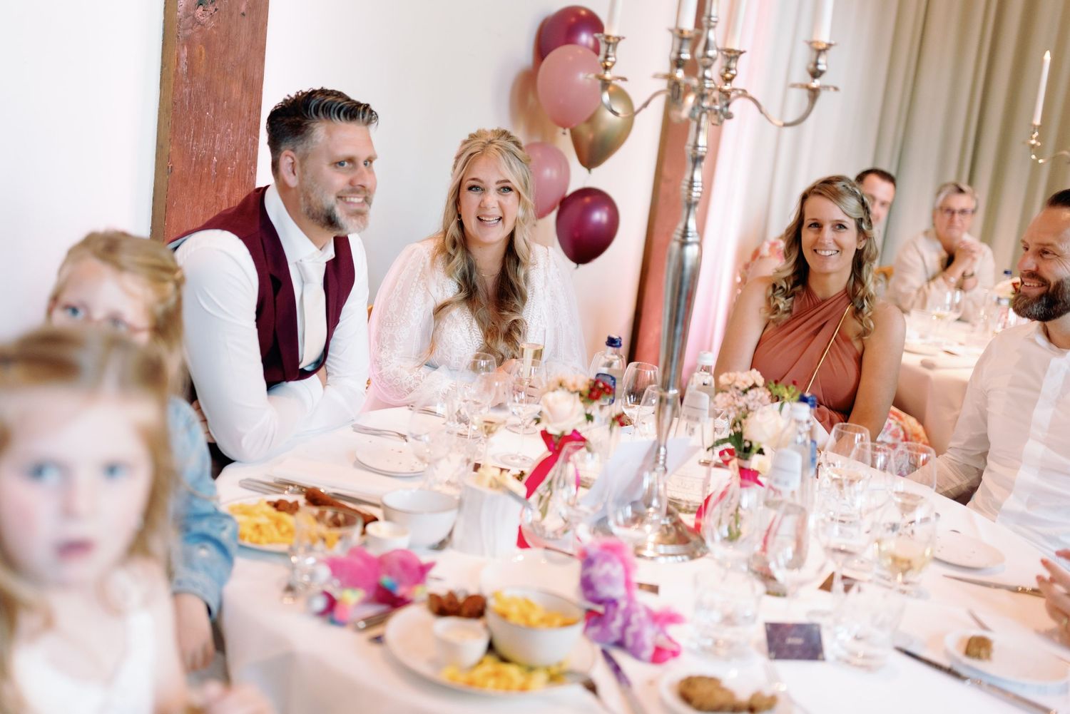 Wedding reception table decorated with pink floral arrangements and glowing candles in an elegant dining room.