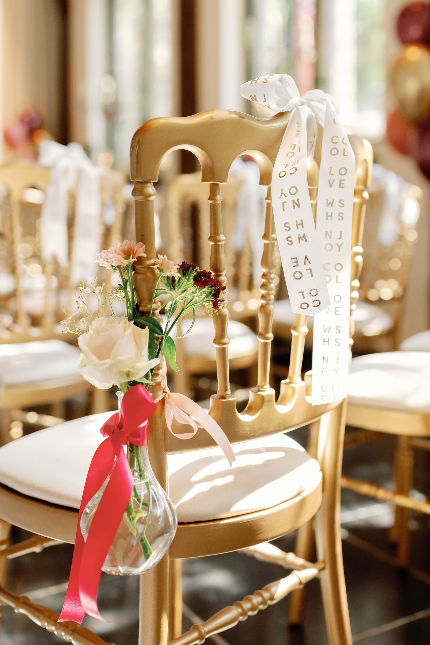 Elegant gold chiavari chairs decorated with floral arrangements and ribbons at a formal wedding reception table setting.