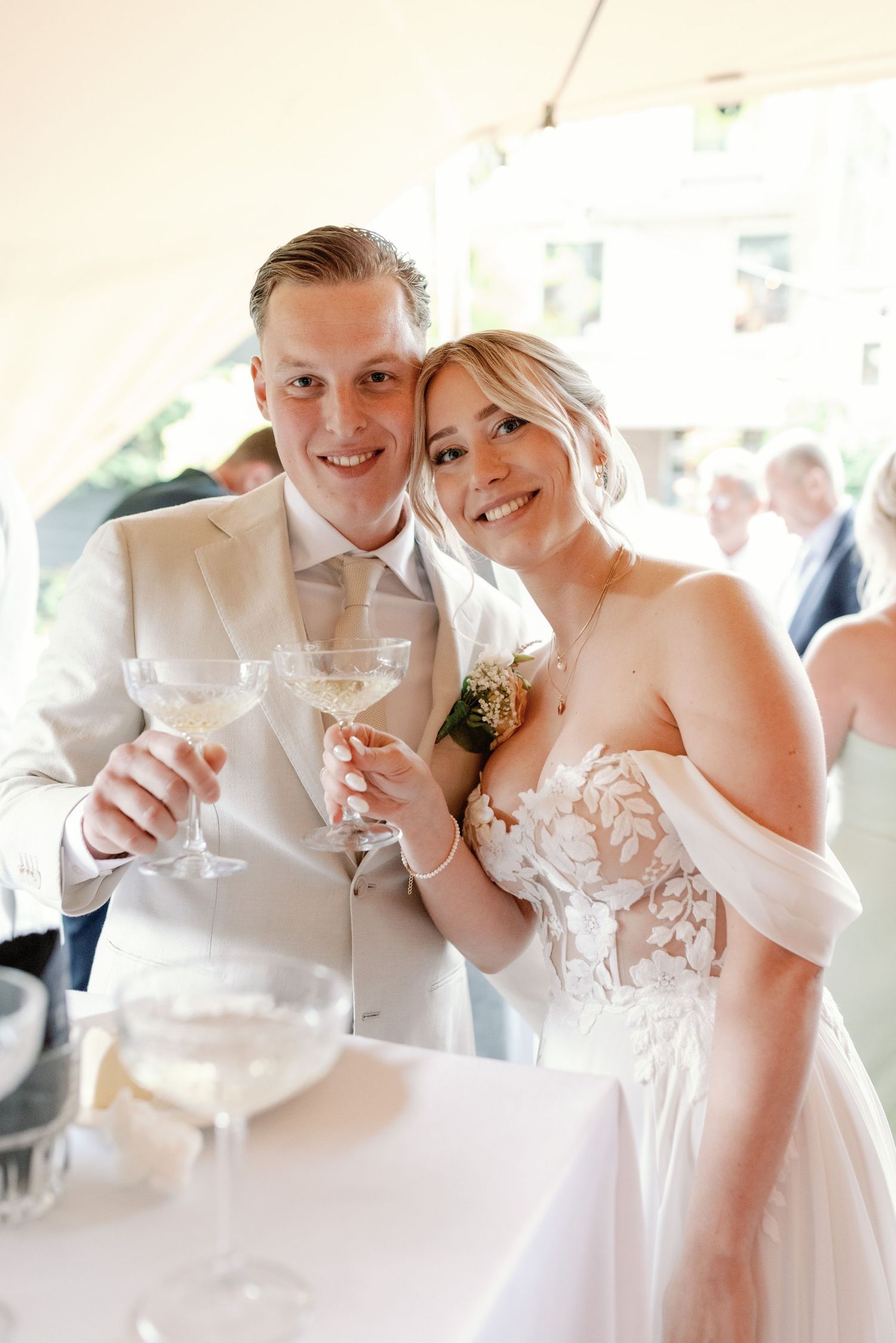 Wedding celebration scene with guests toasting champagne glasses in a bright reception venue.