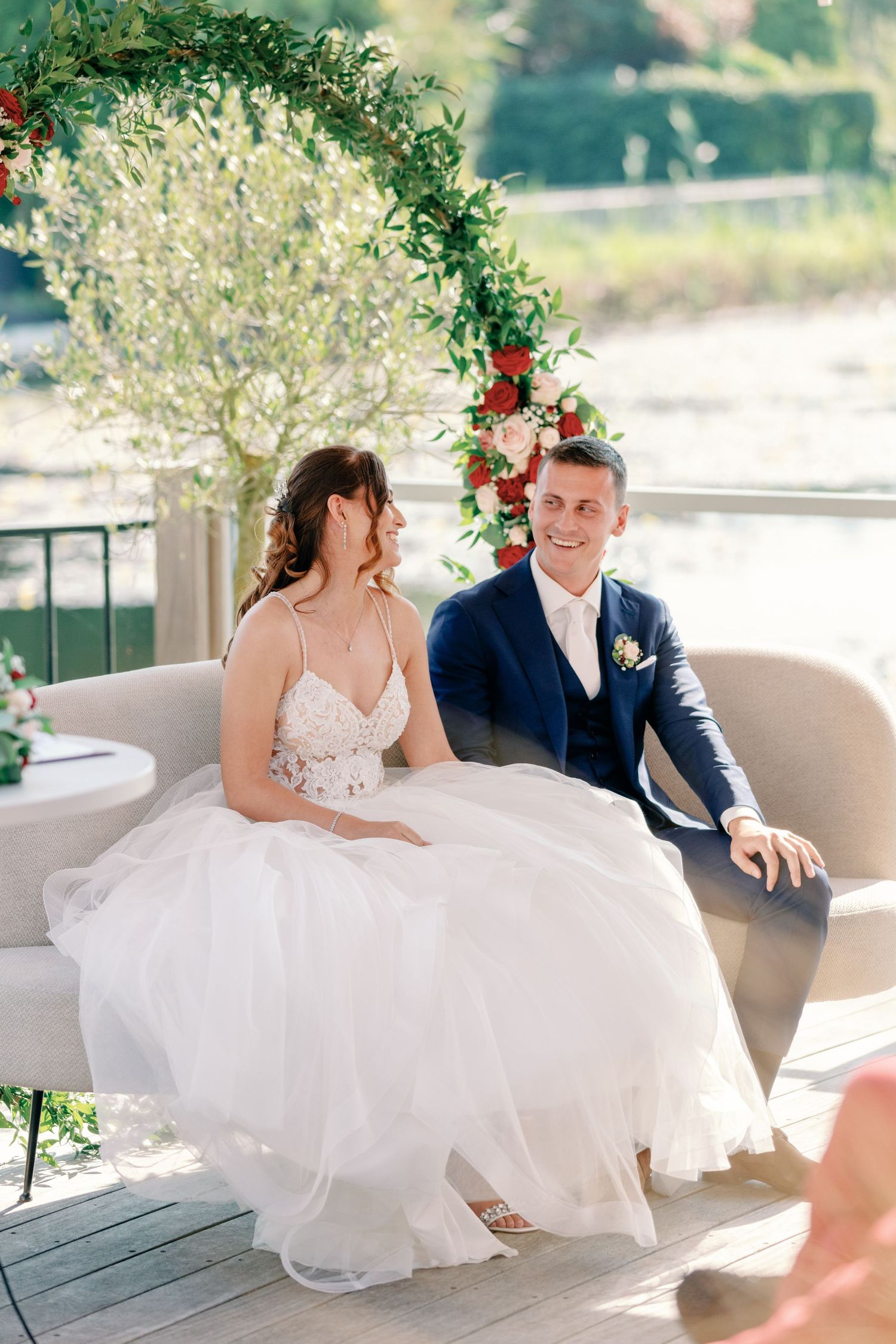 A couple shares a relaxed moment on a patio couch during their wedding celebration.