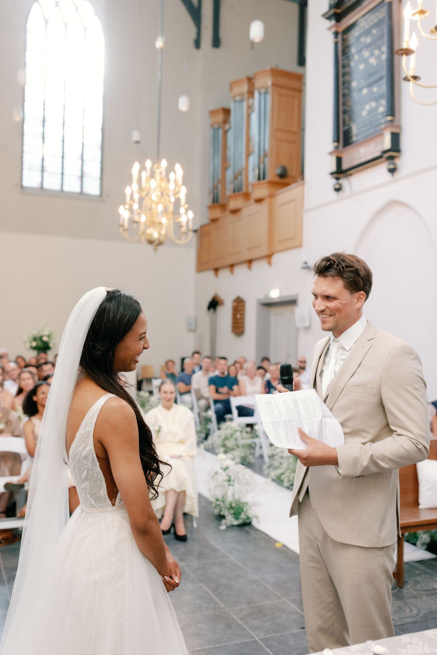 A couple shares their first dance in an elegant church with chandeliers and stone floors during their wedding celebration.