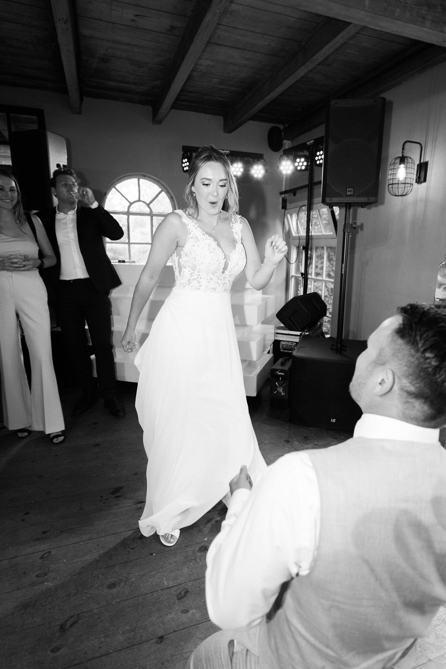 A couple shares their first dance at a wedding reception in a rustic venue with wooden beams and warm lighting.