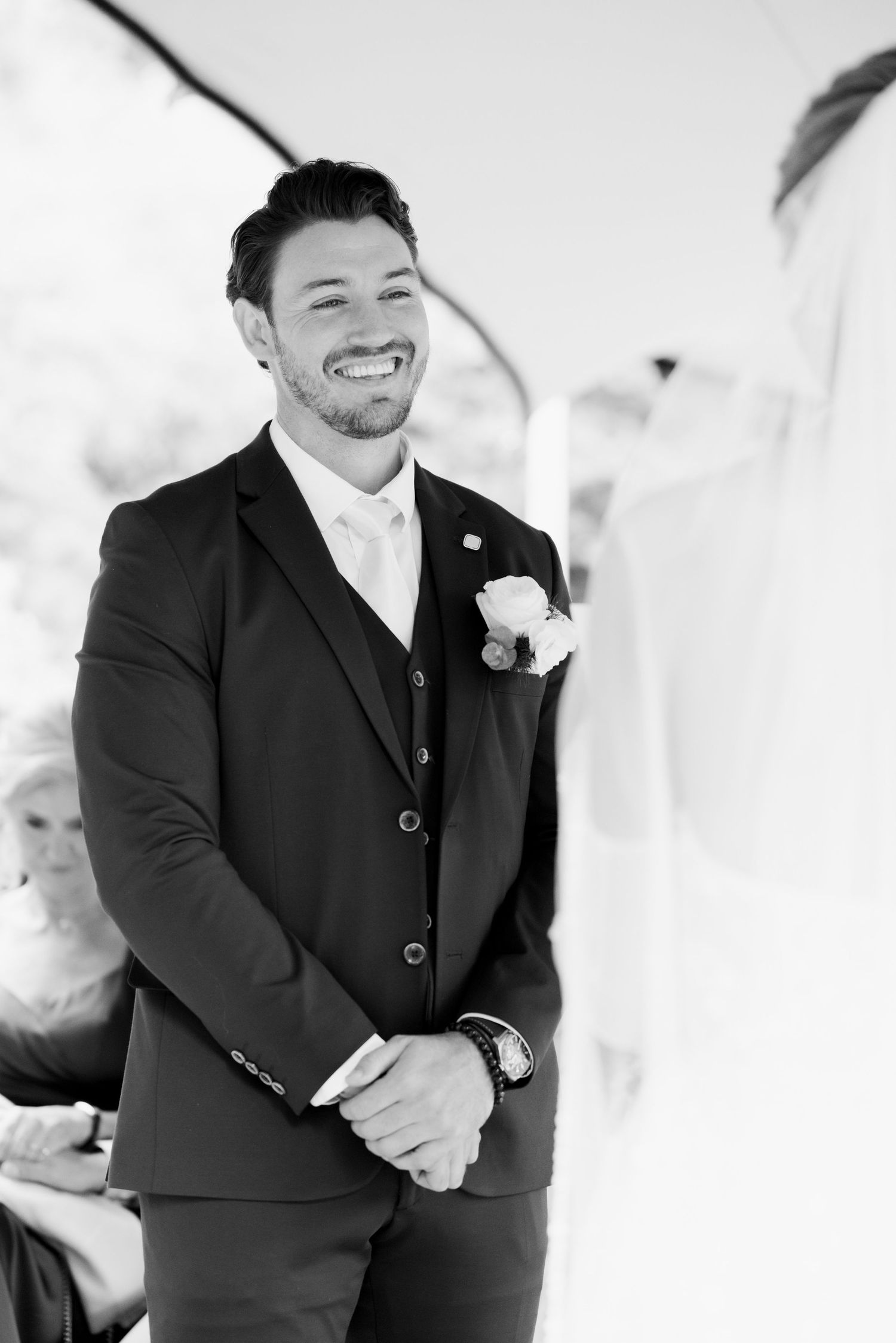 Black and white photo series showing a joyful person in a formal suit laughing during what appears to be a wedding event.