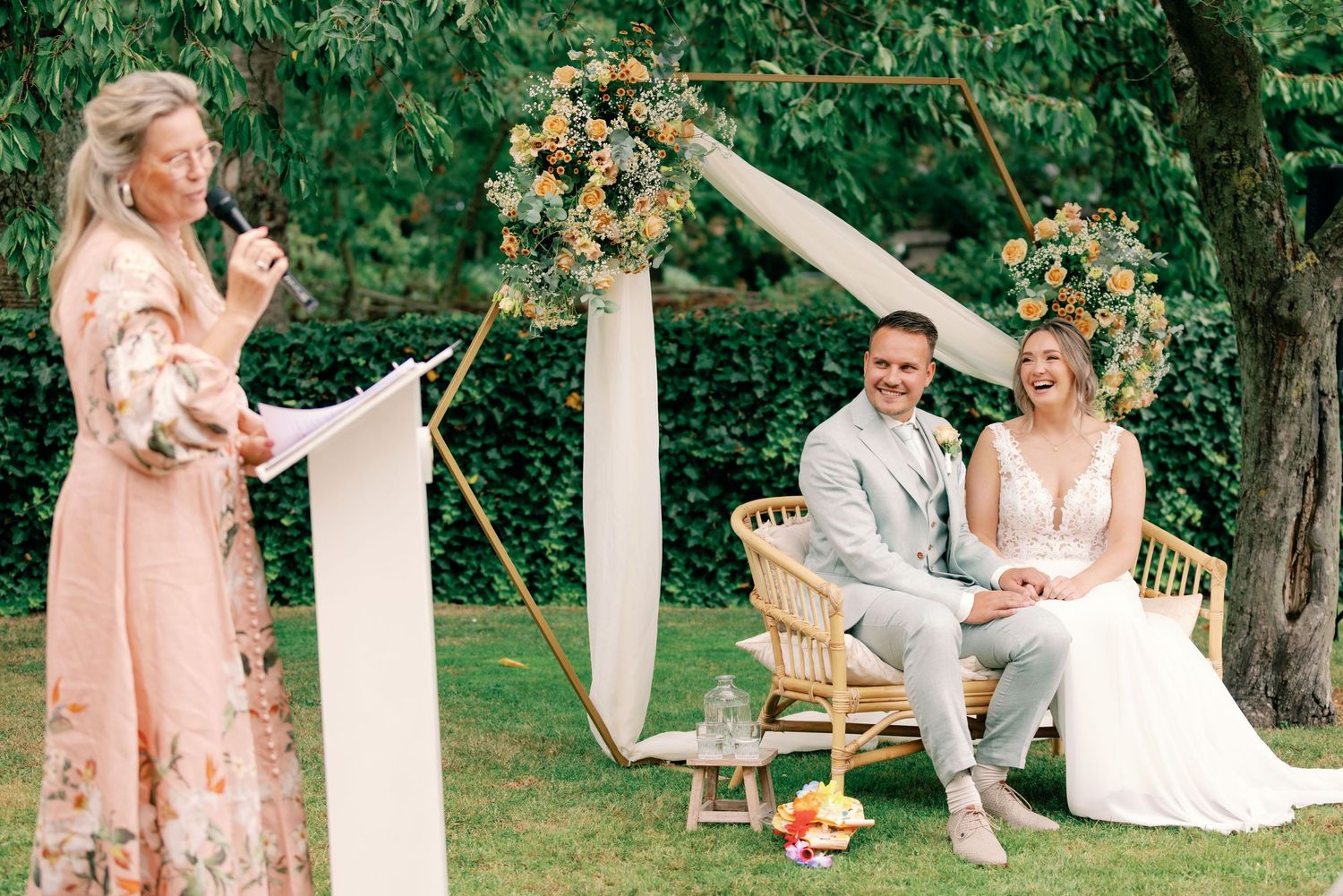 Wedding couple shares intimate moments in a garden setting with pink and neutral color palette and natural greenery.