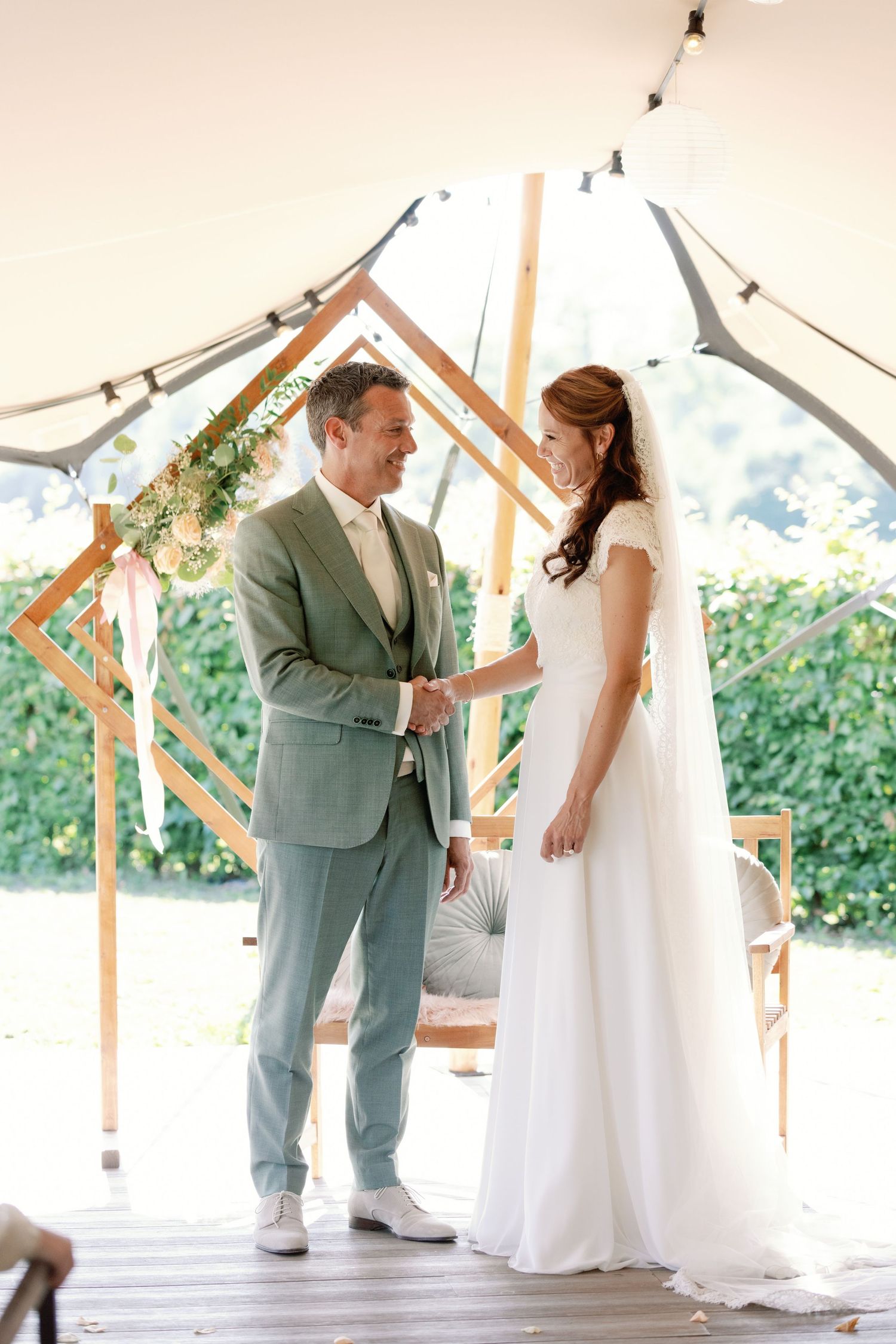 A couple shares their first dance together under a white tent canopy during their wedding celebration.