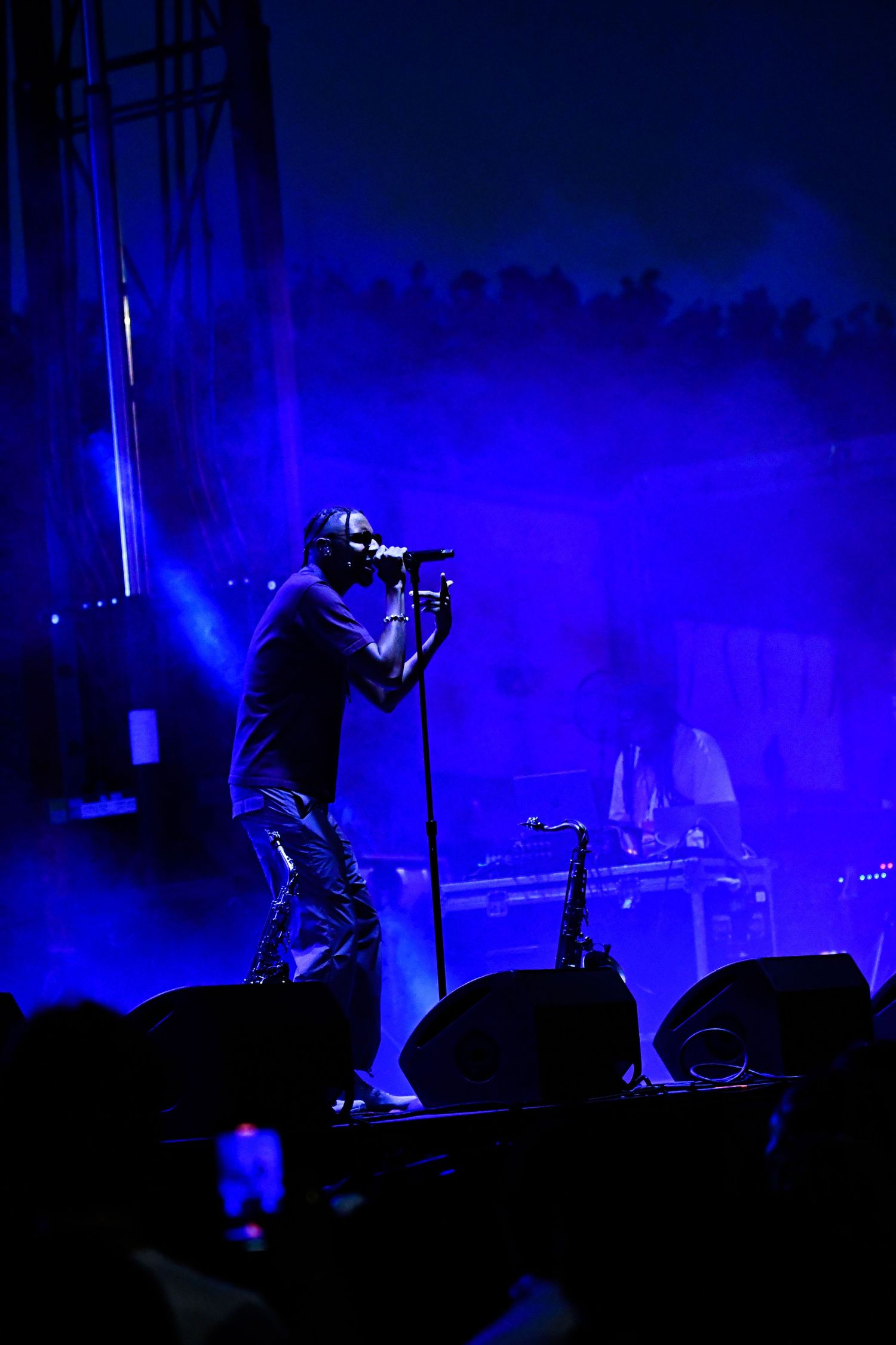 Silhouetted performer on stage against dramatic blue lighting during concert performance.