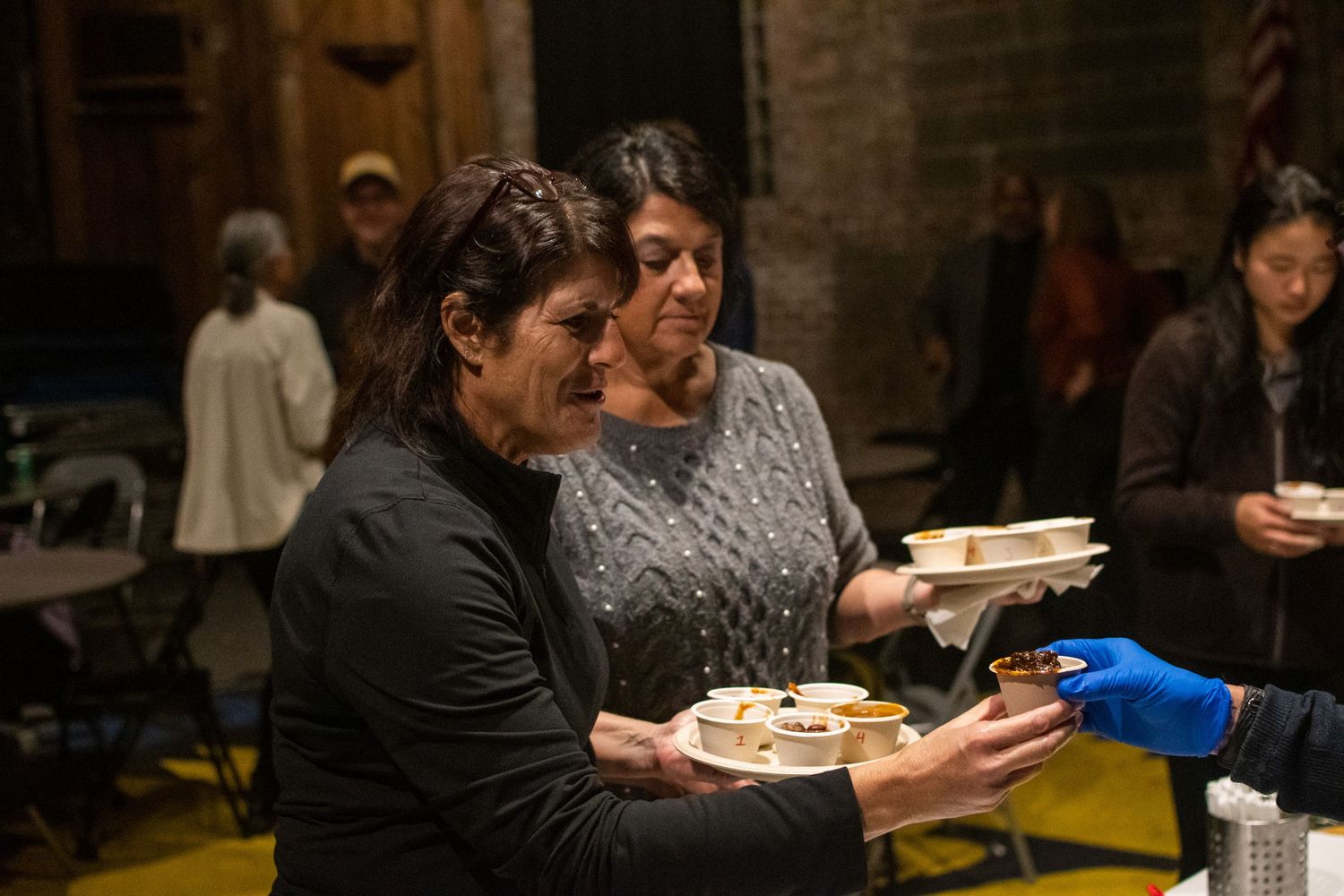 A group of diners share dishes and enjoy a meal together at a restaurant with brick walls.