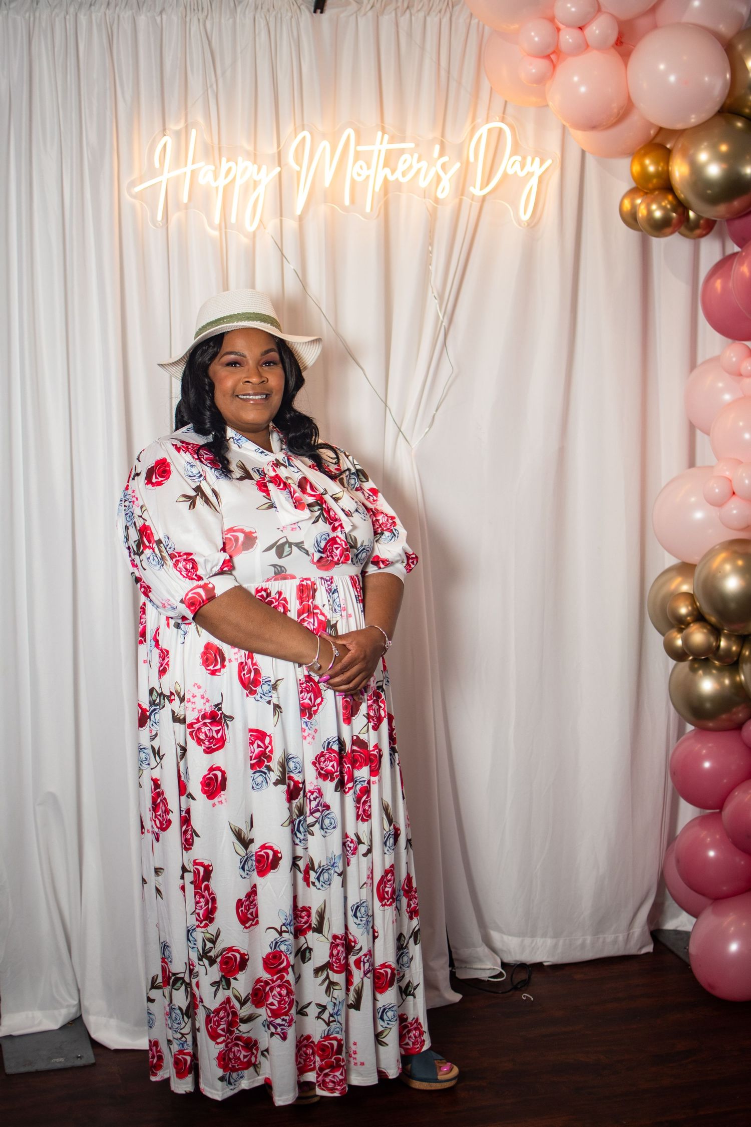 Party setup with pink and gold balloons against white backdrop with neon lighting.