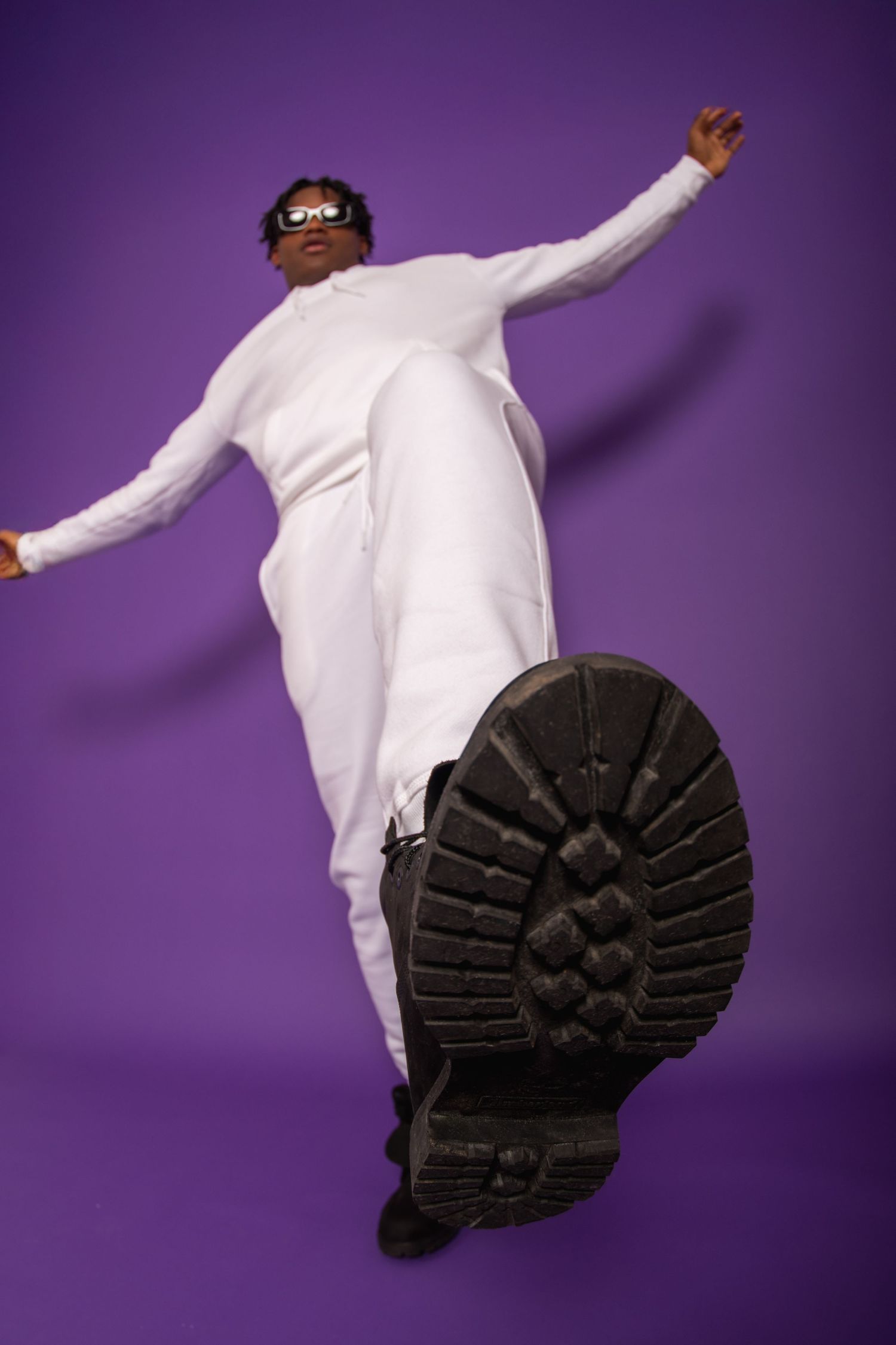 A dancer in white clothing performs a dynamic pose against a purple backdrop, showing movement from different angles.