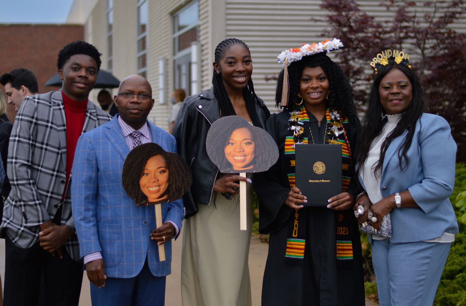A group of students wearing graduation stoles and regalia gather together for a celebratory photo.
