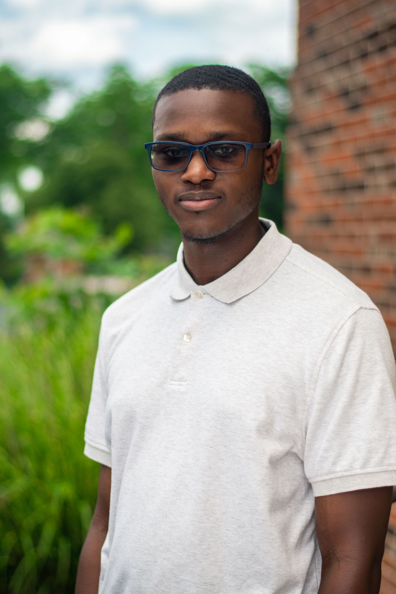 Outdoor professional portraits showing confident poses in white polo shirt against brick wall.