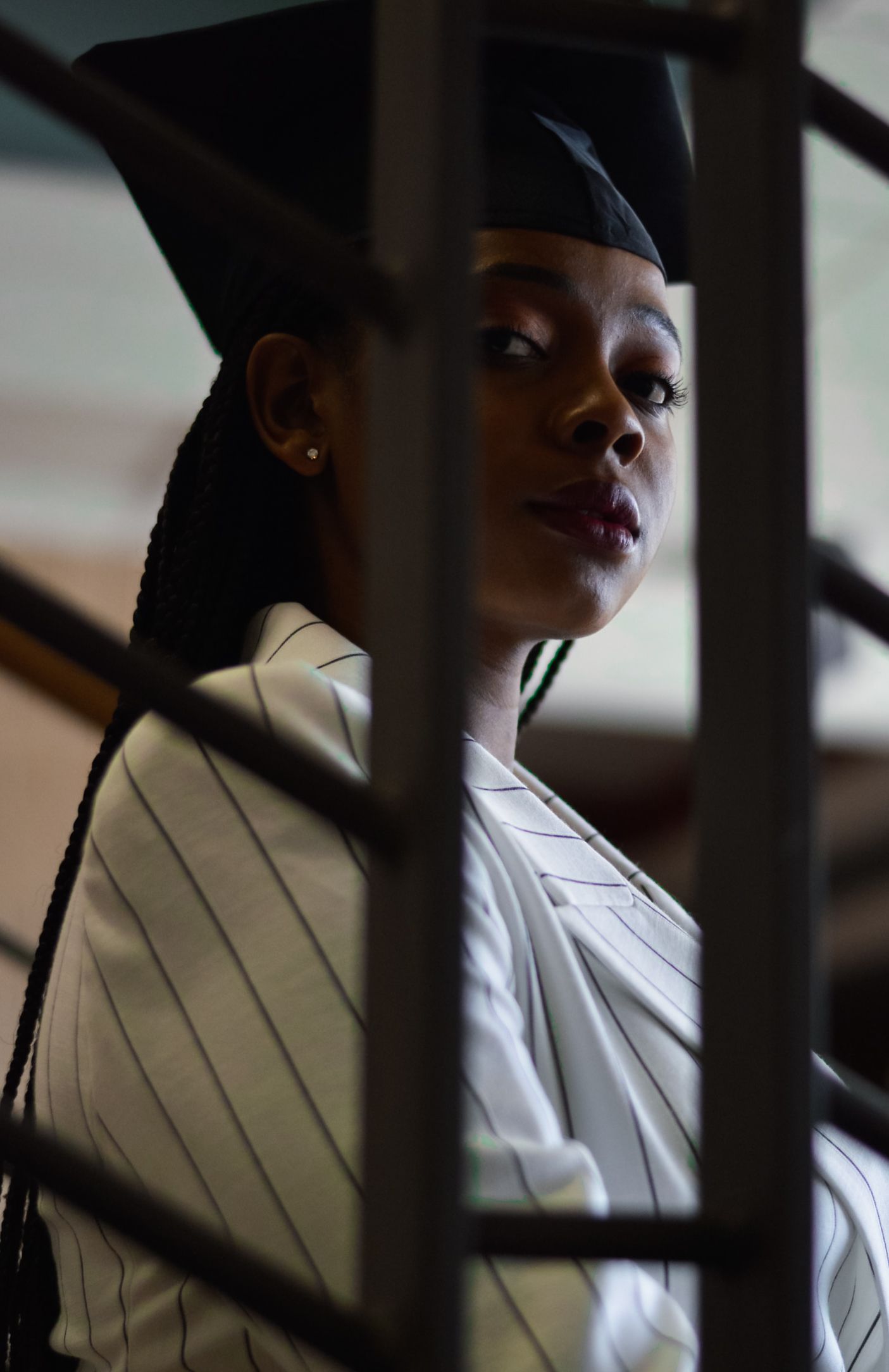 Artistic portrait of graduate through architectural elements creating dramatic shadows.