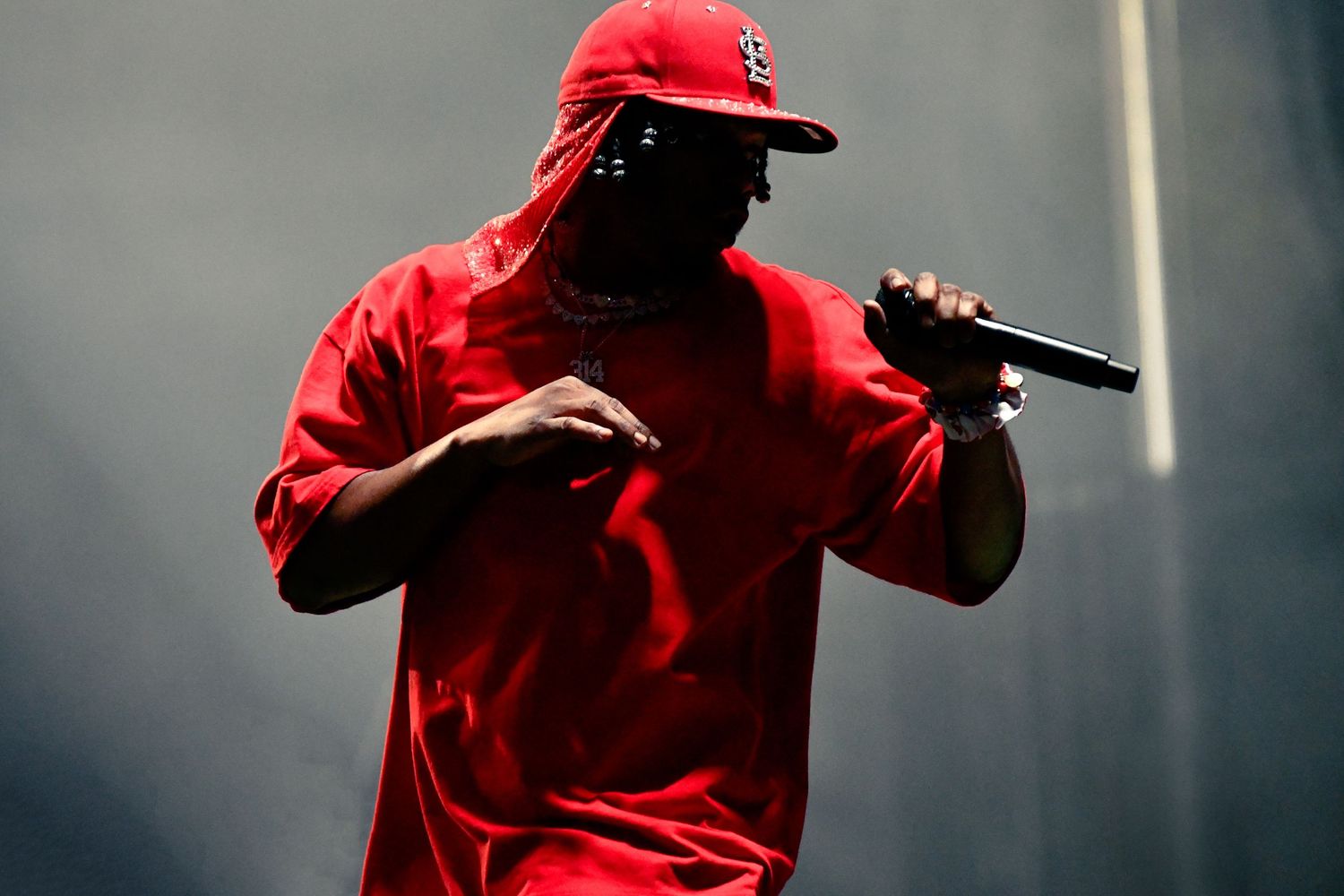 A performer in a bright red jacket stands on stage during a concert performance.