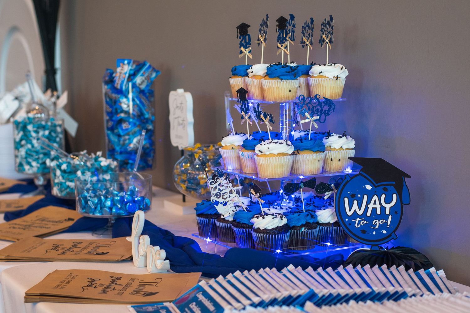 Blue and white dessert table setup with candles, cupcakes and decorative elements for a party celebration.