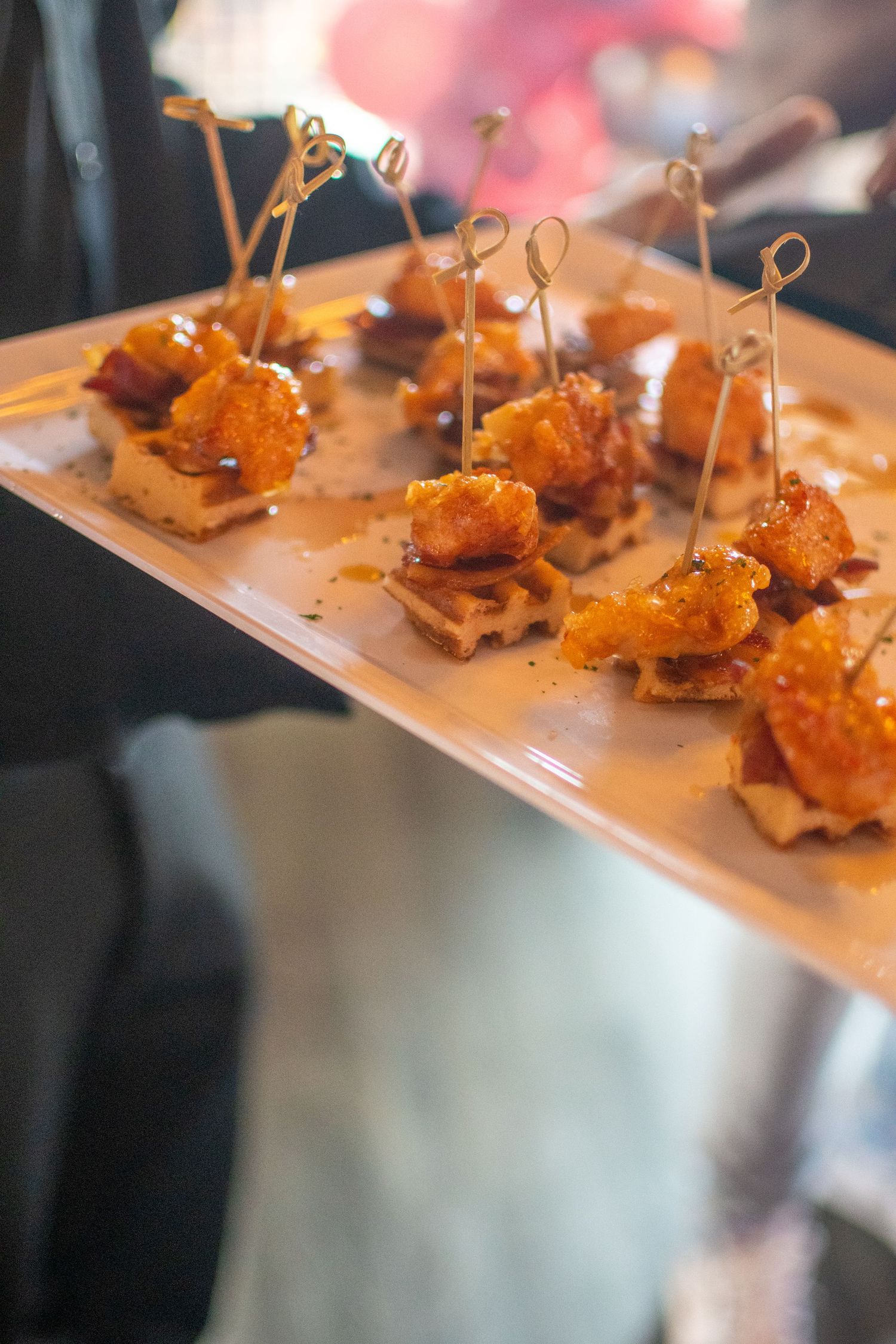 Gourmet appetizers with crispy toppings arranged on a wooden serving board at an upscale event.