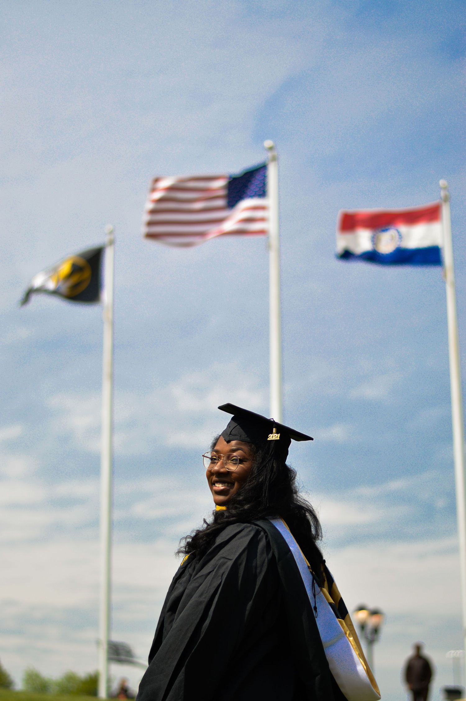 Graduate celebrating achievement with American flags waving in background.