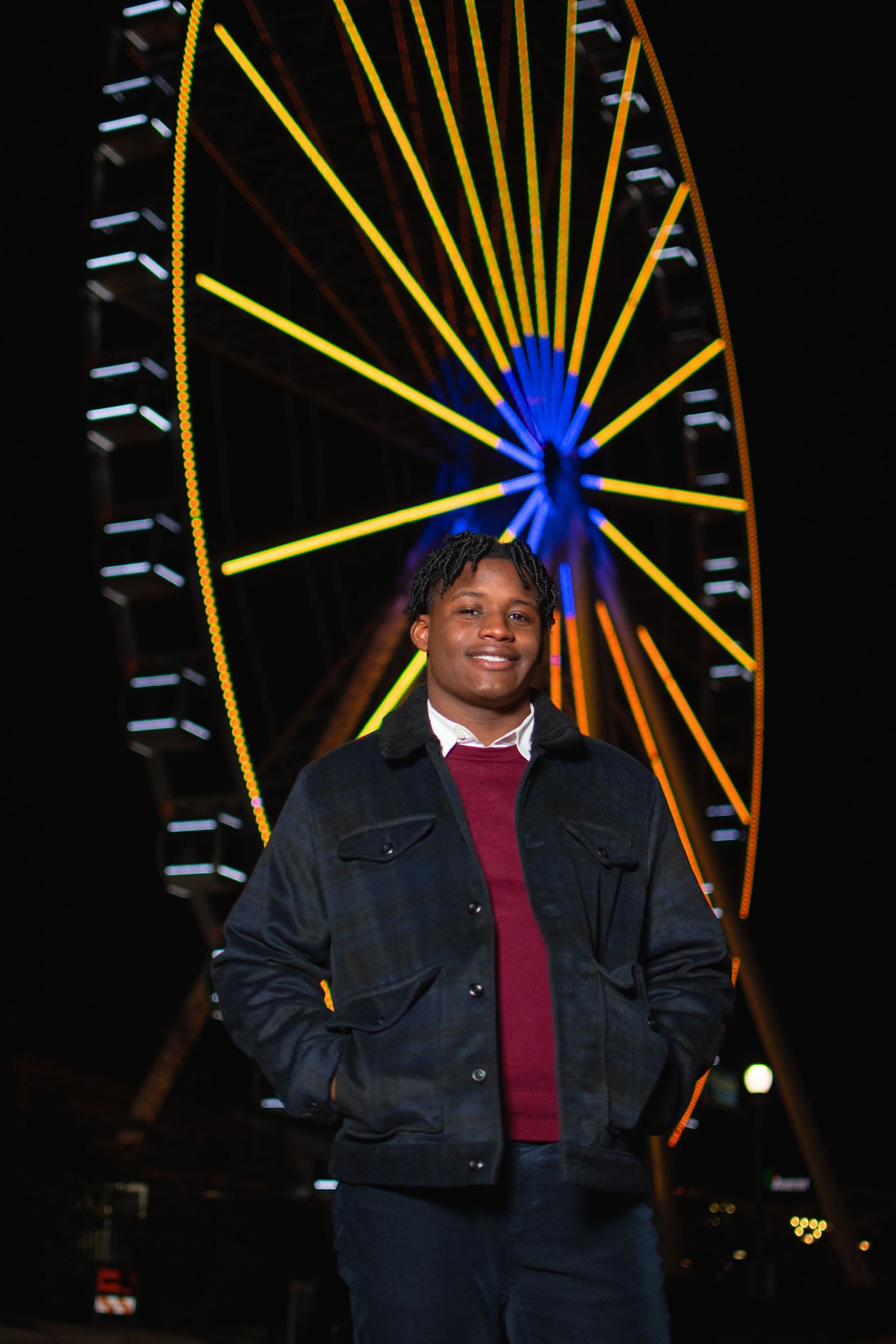 A dark nighttime scene with a glowing yellow ferris wheel illuminated against the black sky.