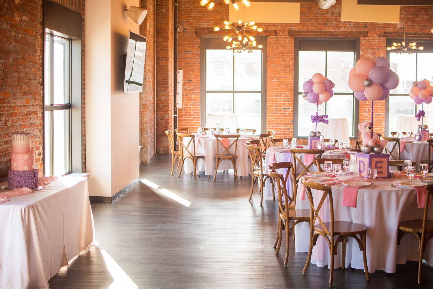 An elegant wedding reception venue with exposed brick walls and round tables decorated in white linens.