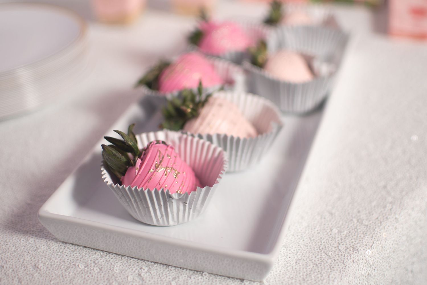 Pink frosted cupcakes arranged on tiered white serving platters.