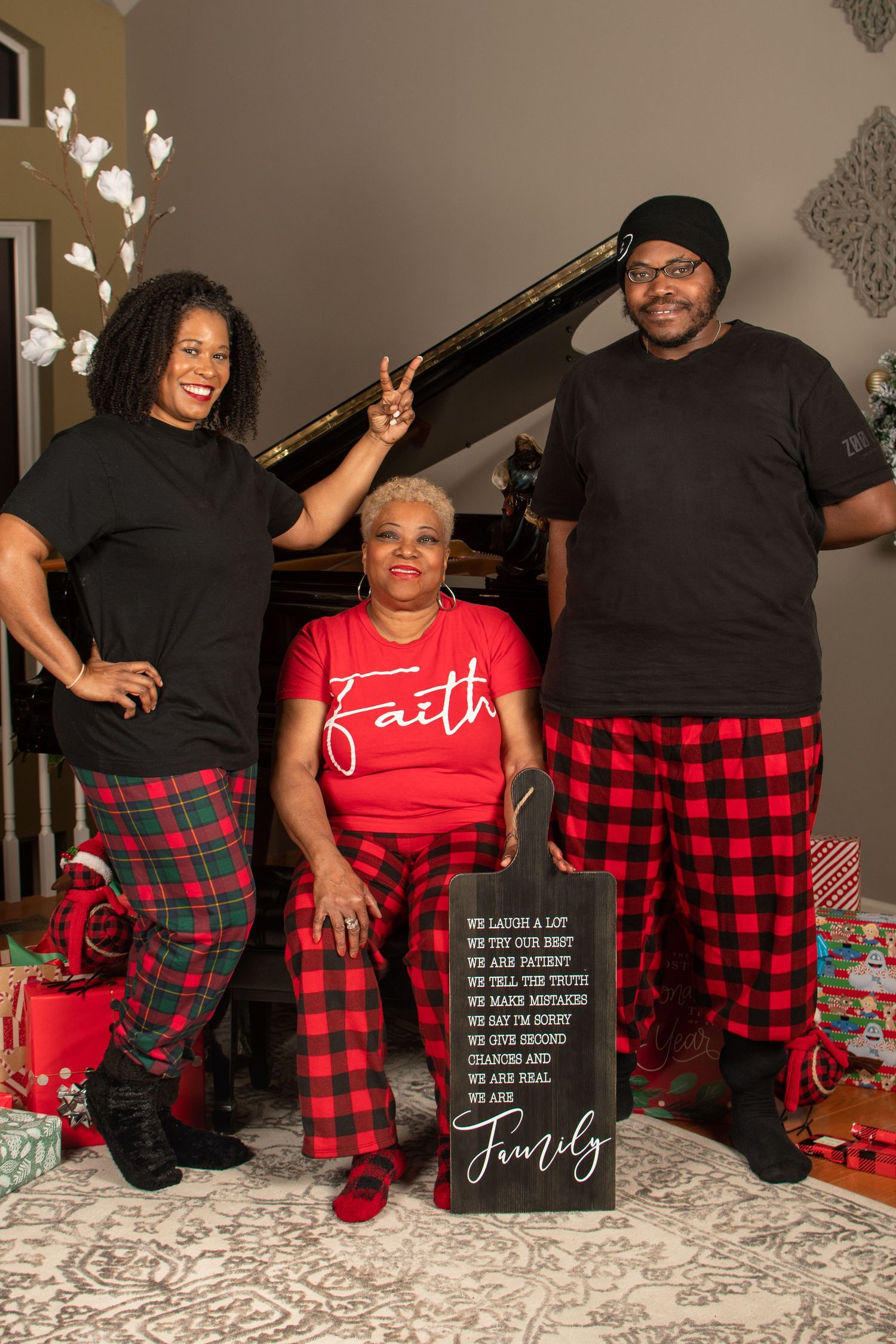 Group wearing matching red and black plaid pajamas posing with holiday decorations.