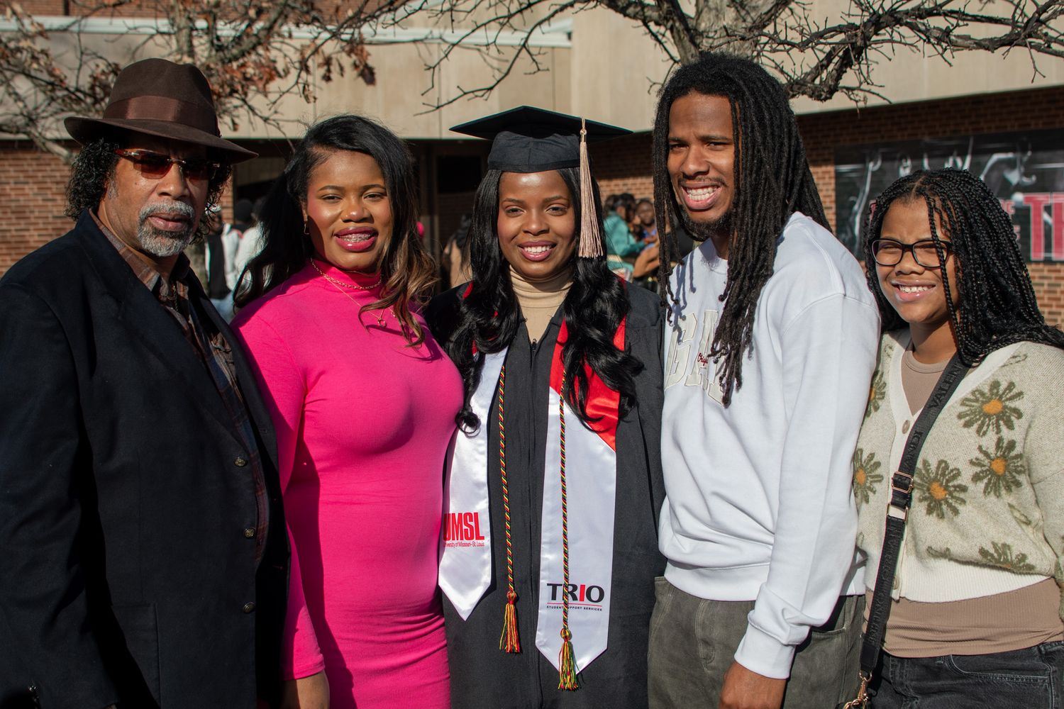 A group of graduates in caps and gowns celebrate together with family members at a commencement ceremony.