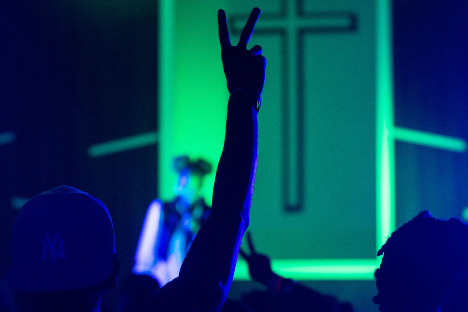 Silhouetted figures dance with raised arms against a vibrant blue and green nightclub background.
