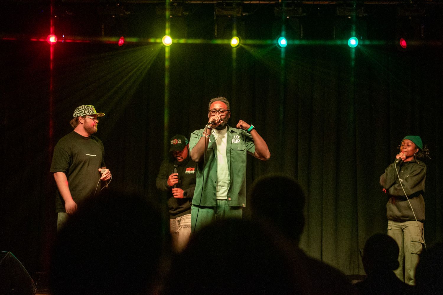 A series of performers on stage under colored lights during a comedy show performance.